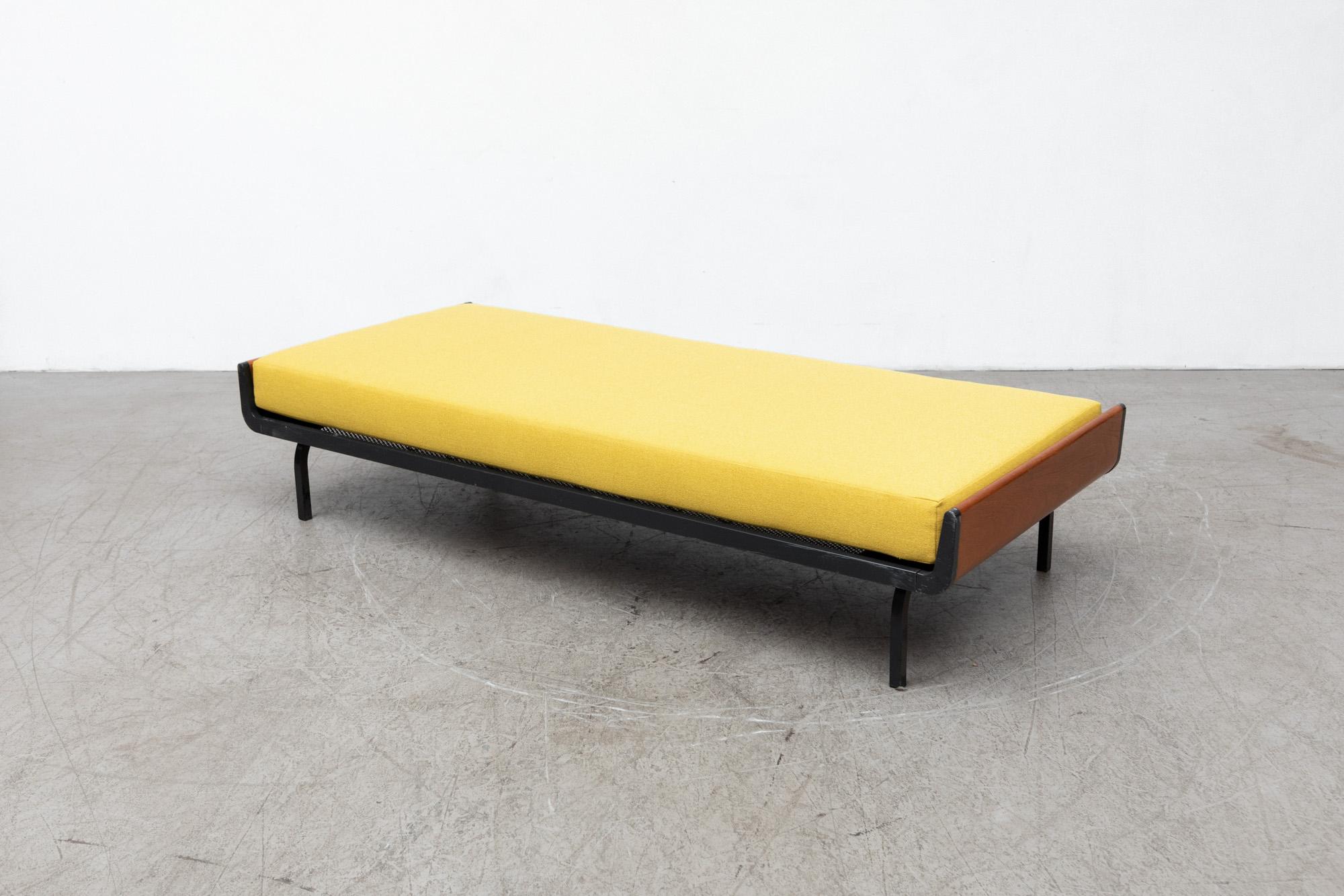 Mid-Century Friso Kramer style daybed with lightly refinished upturned teak ends and dark grey enameled metal frame for Auping. Freshly upholstered sunshine yellow mattress on wire mesh support with original manufacturer stamp. Frames may vary. In