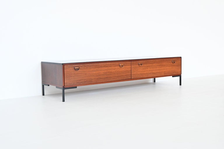 Beautiful refined quality low sideboard manufactured by Fristho Franeker, The Netherlands 1960. This sideboard is made of nicely grained rosewood veneer with a black lacquered top supported by four metal feet. It has two wide folding doors with