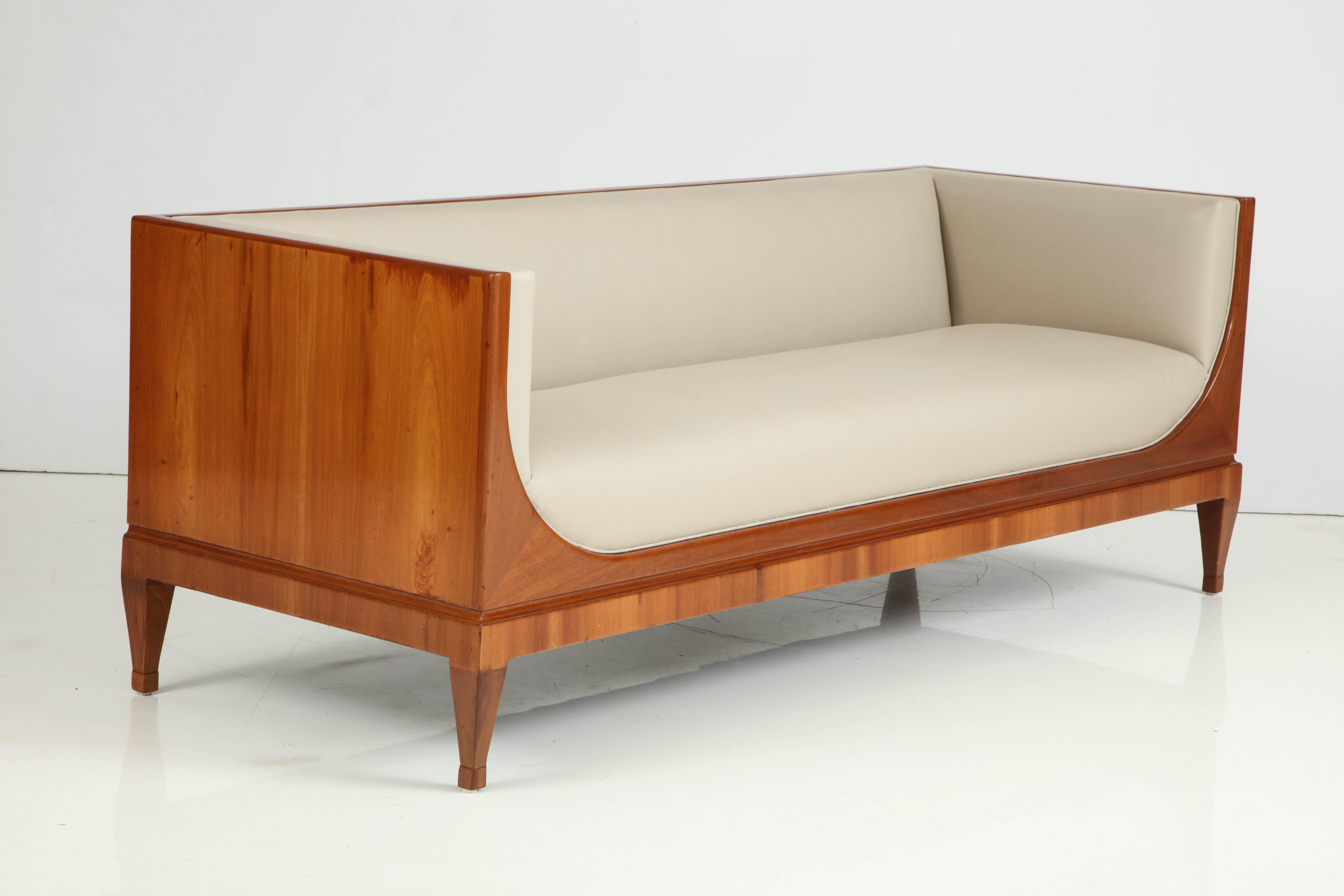 A Classic Frits Henningsen rich mahogany and upholstered sofa, circa 1930s, rectangular upholstered backrest and sides, front frieze with graceful curved ends, above a recessed plinth base raised on square tapered legs ending with blocks.
Original