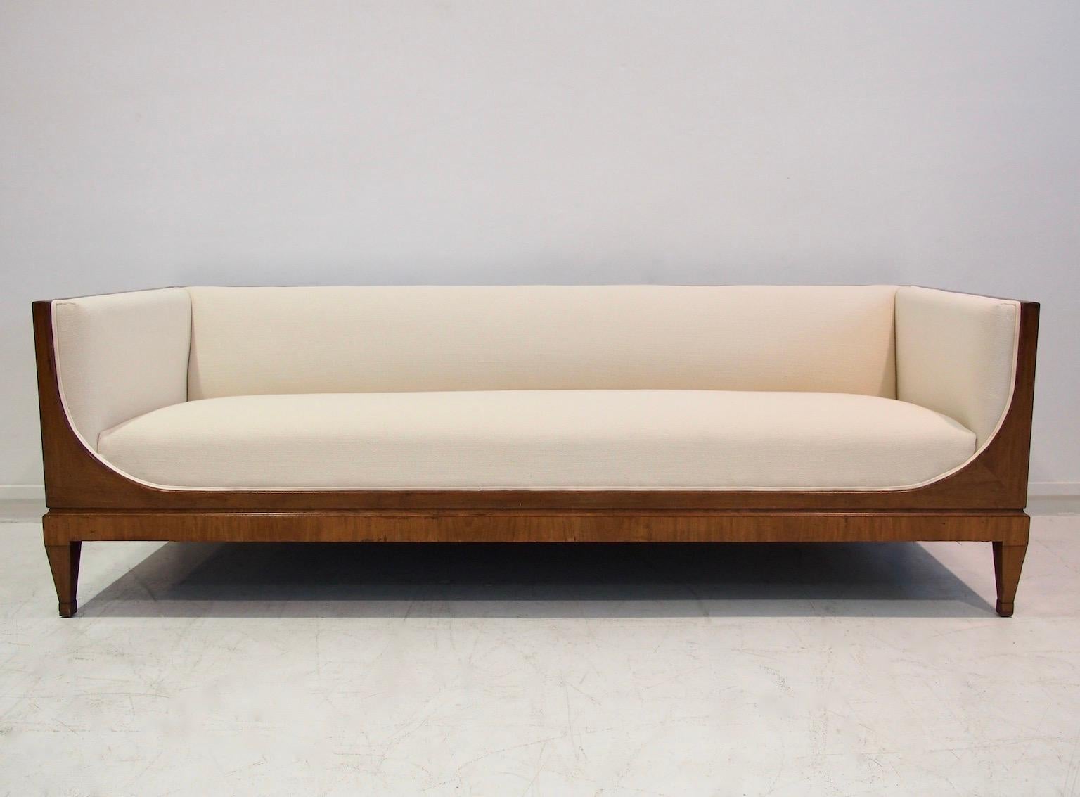 Beautiful box-shaped three-seater mahogany sofa by cabinetmaker Frits Henningsen from circa 1940. Front with rounded sleigh-shaped sides, tapered legs. Seat and back reupholstered in with off-white textured fabric. 