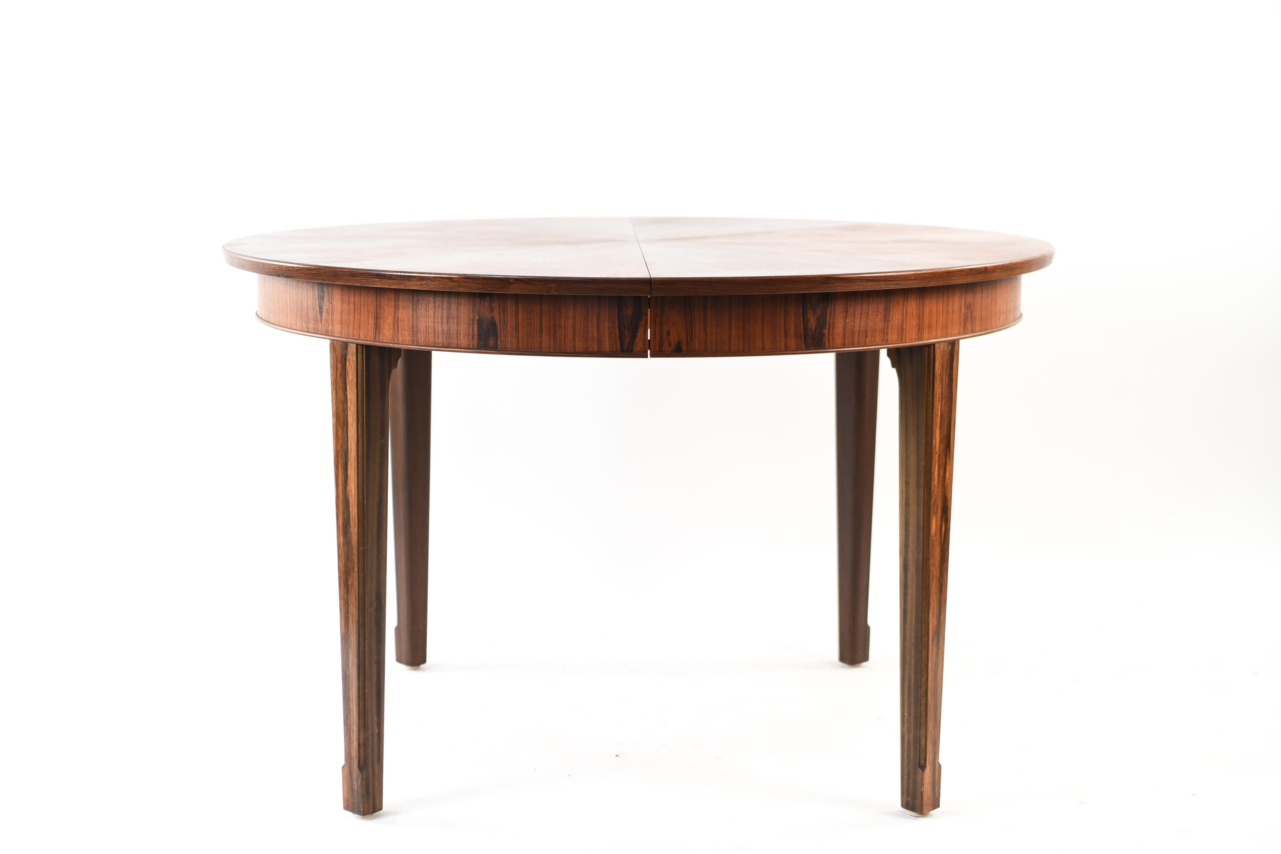 This Danish midcentury rosewood dining table by Frits Henningsen has a handsome radial veneer on the top that accentuates the unusual circular form. This is an exemplary showcase of Henningsen's well sought after work. Includes one original leaf and