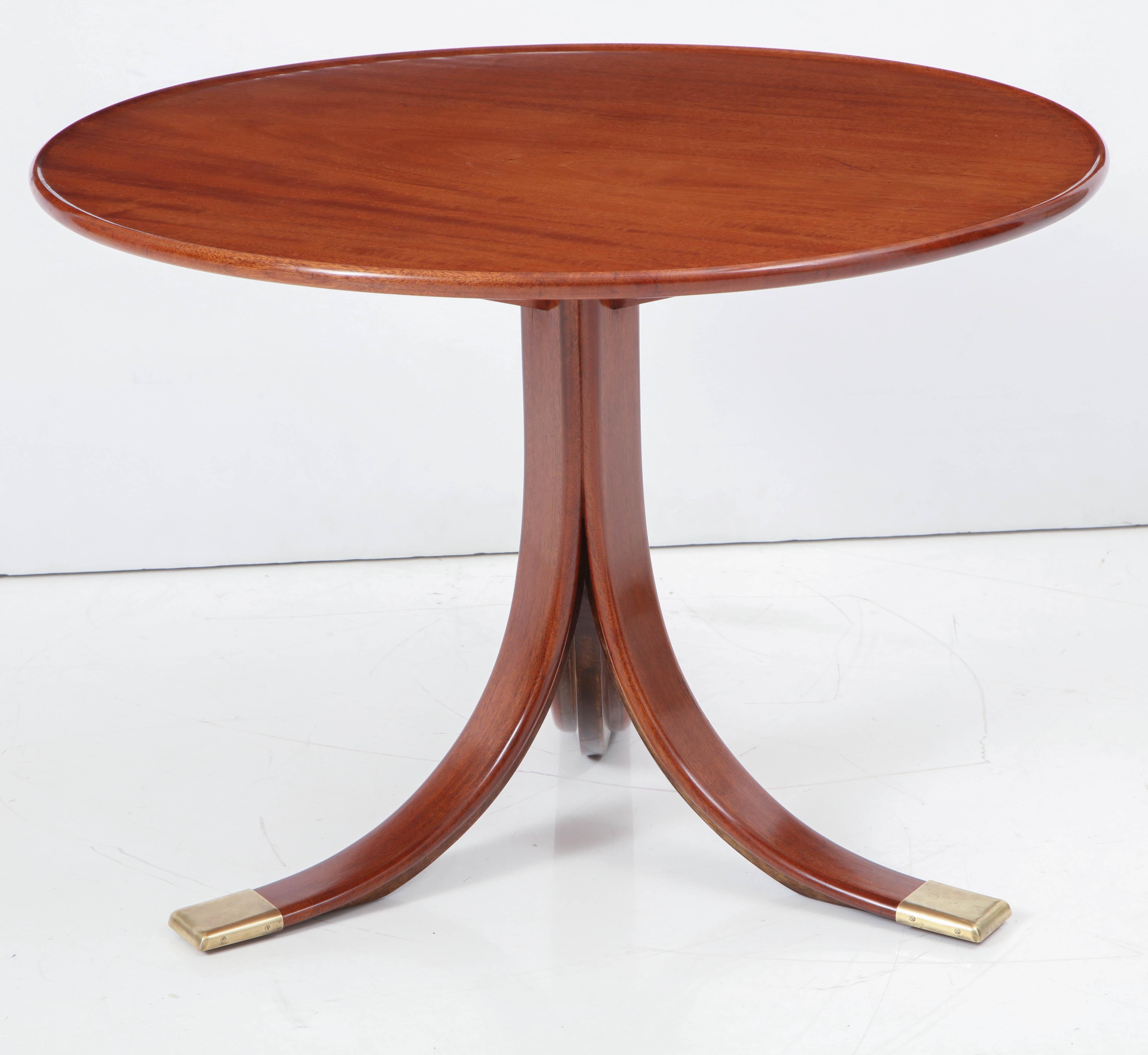 A Danish well figured mahogany and brass-mounted side table designed and produced by Frits Henningsen, circa1940s, the solid circular top with a lipped edge, raised on a wide downswept leg tripod base ending with brass sabots.