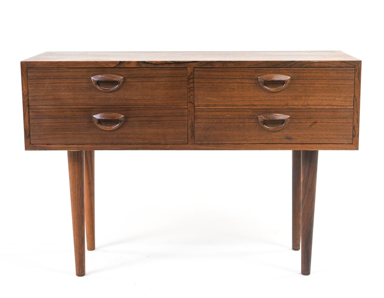 An exquisite Kai Kristiansen Danish mid-century petite four-drawer chest in rosewood veneer, with shaped drawer pulls, on tapered legs. Clean maple drawer interiors.