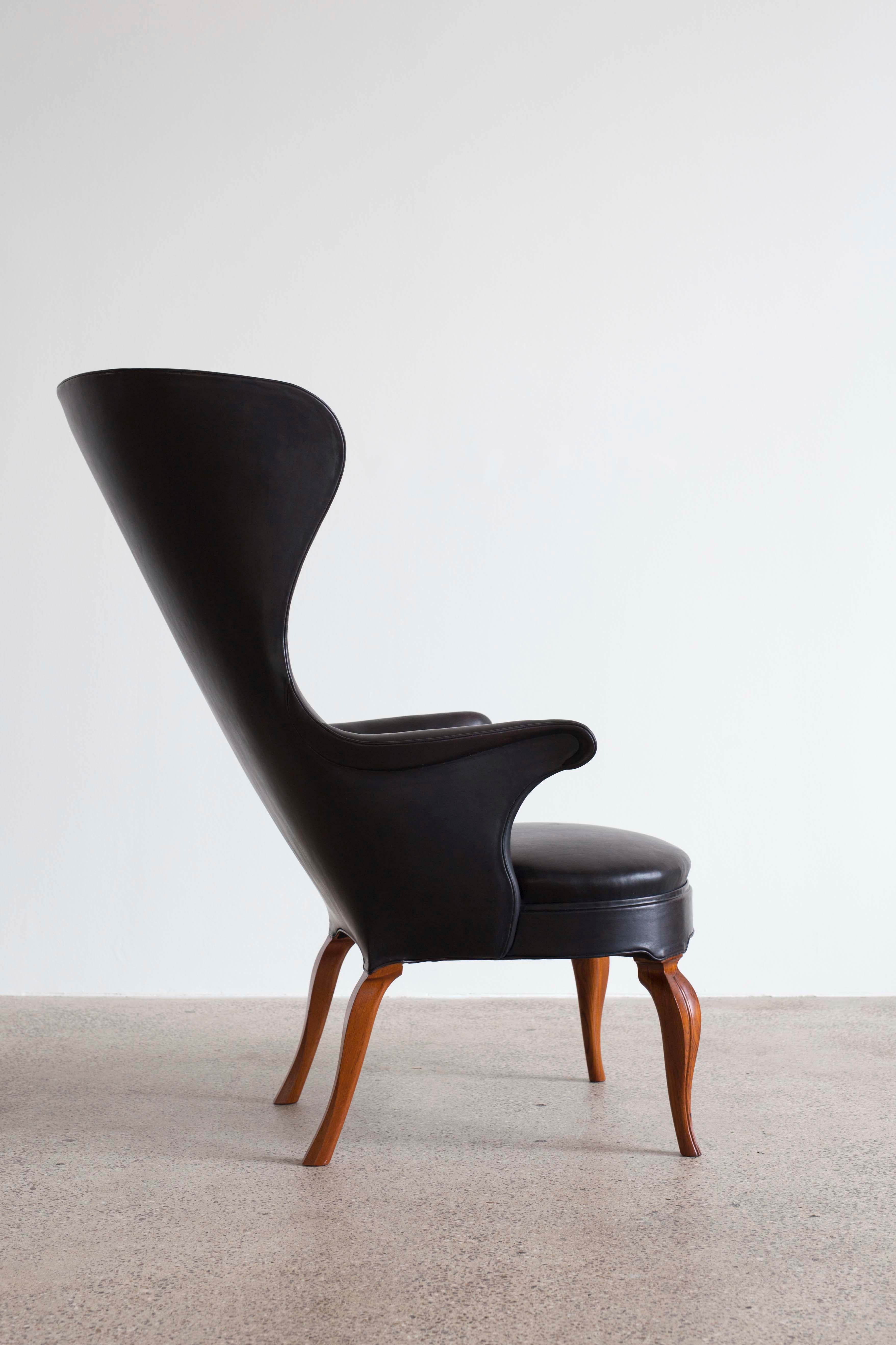 Rare Frits Henningsen high wingback chair upholstered with black natural leather, fitted with buttons. 

Detailed curving legs of mahogany. 

Designed 1935, made by cabinetmaker Frits Henningsen.
