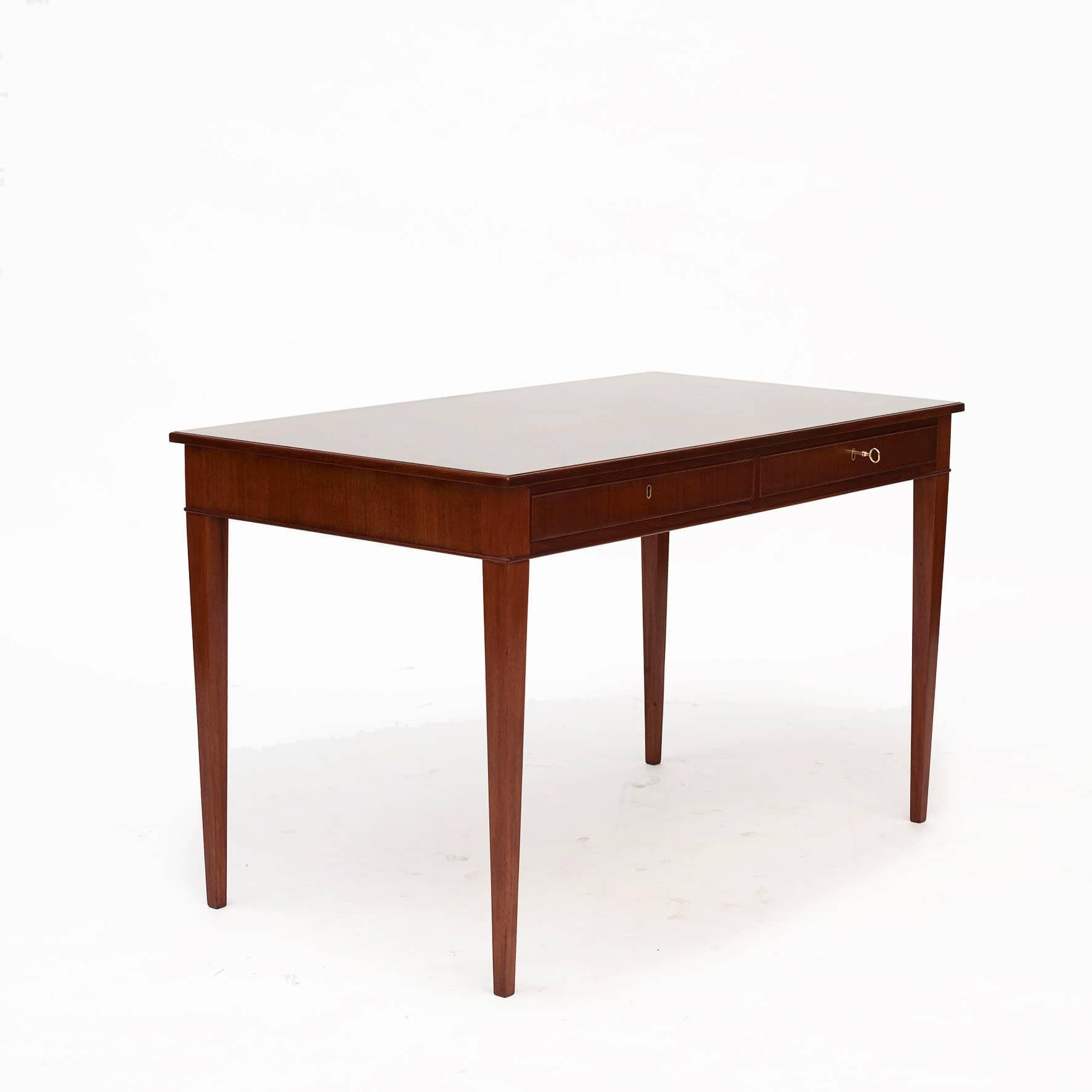 Frits Henningsen, designer de meubles et ébéniste danois (1889-1965).
Elegante table à écrire en acajou massif.
Plateau rectangulaire à bord mouluré au-dessus des tiroirs, reposant sur d'élégants pieds fuselés carrés.

Hauteur du tablier : 60,5