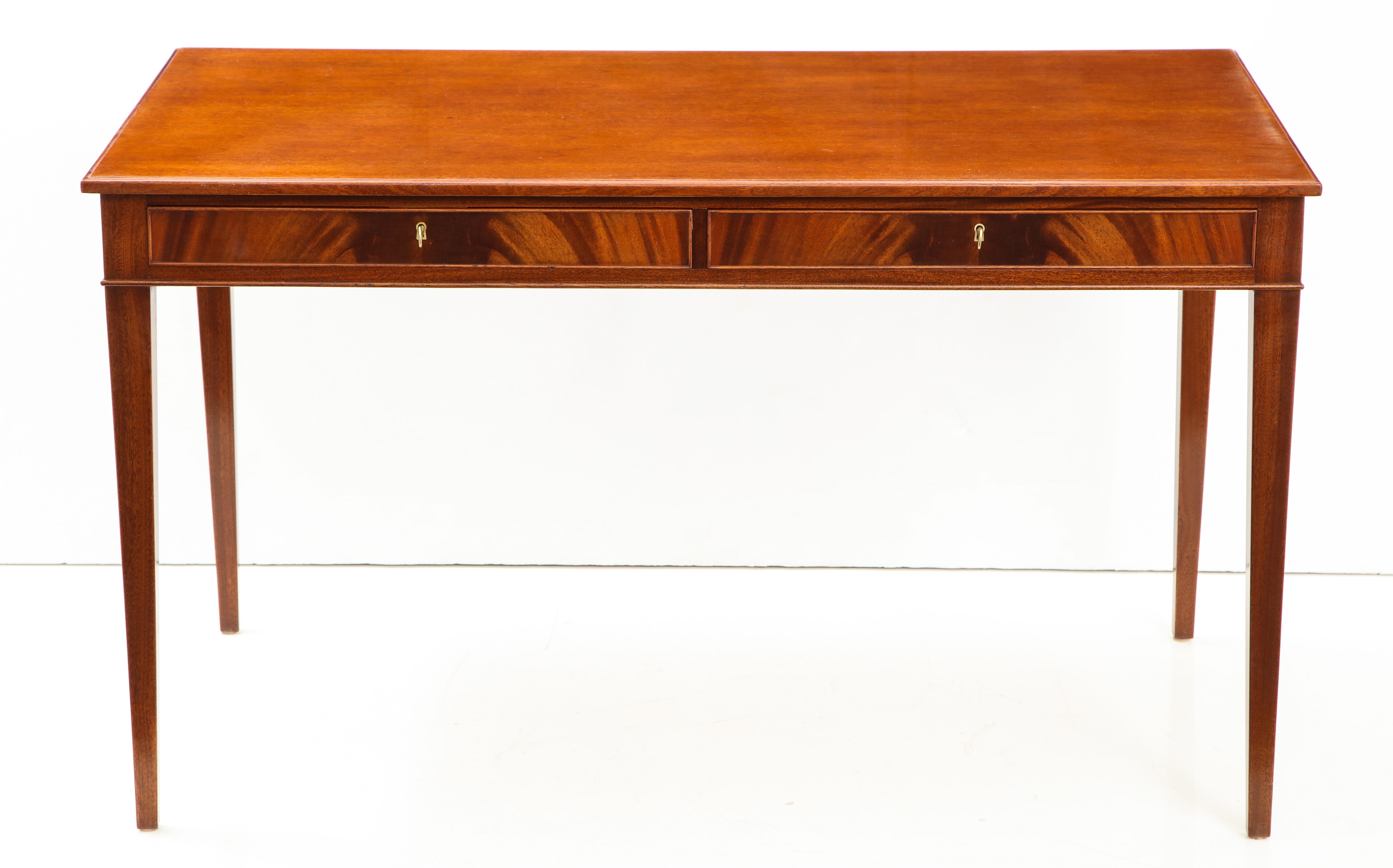 A Danish mahogany writing table by Frits Henningsen, furniture designer and cabinet maker (1889-1965). This desk is a classic example of Henningsen's elegant clean lines and use of quality woods with perfect balanced craftsmanship. A rectangular top