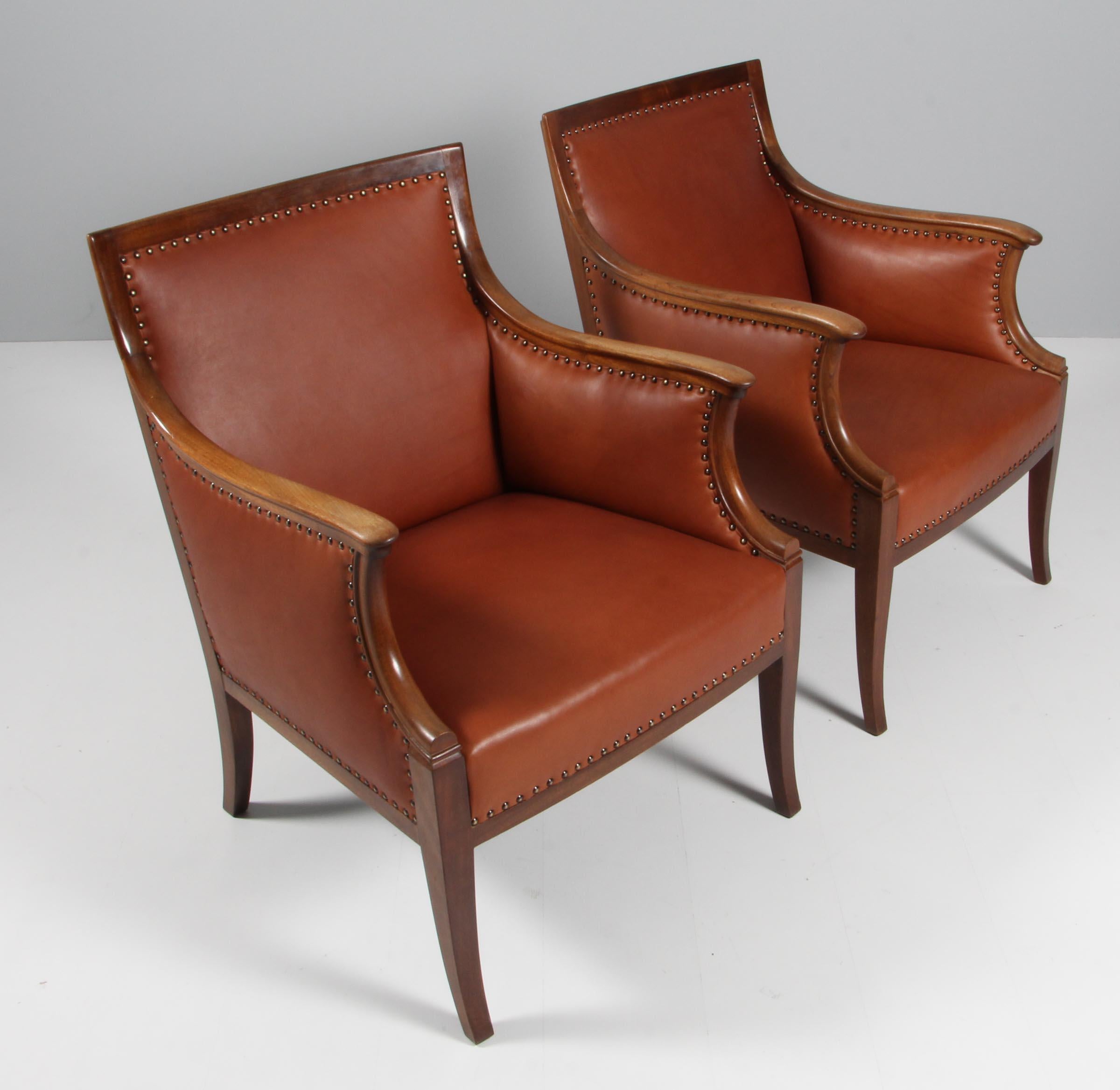 Frits Henningsen pair of lounge chairs new upholstered with brandy coloured aniline leather.

Frame of mahogany. 

Made in the 1940s.