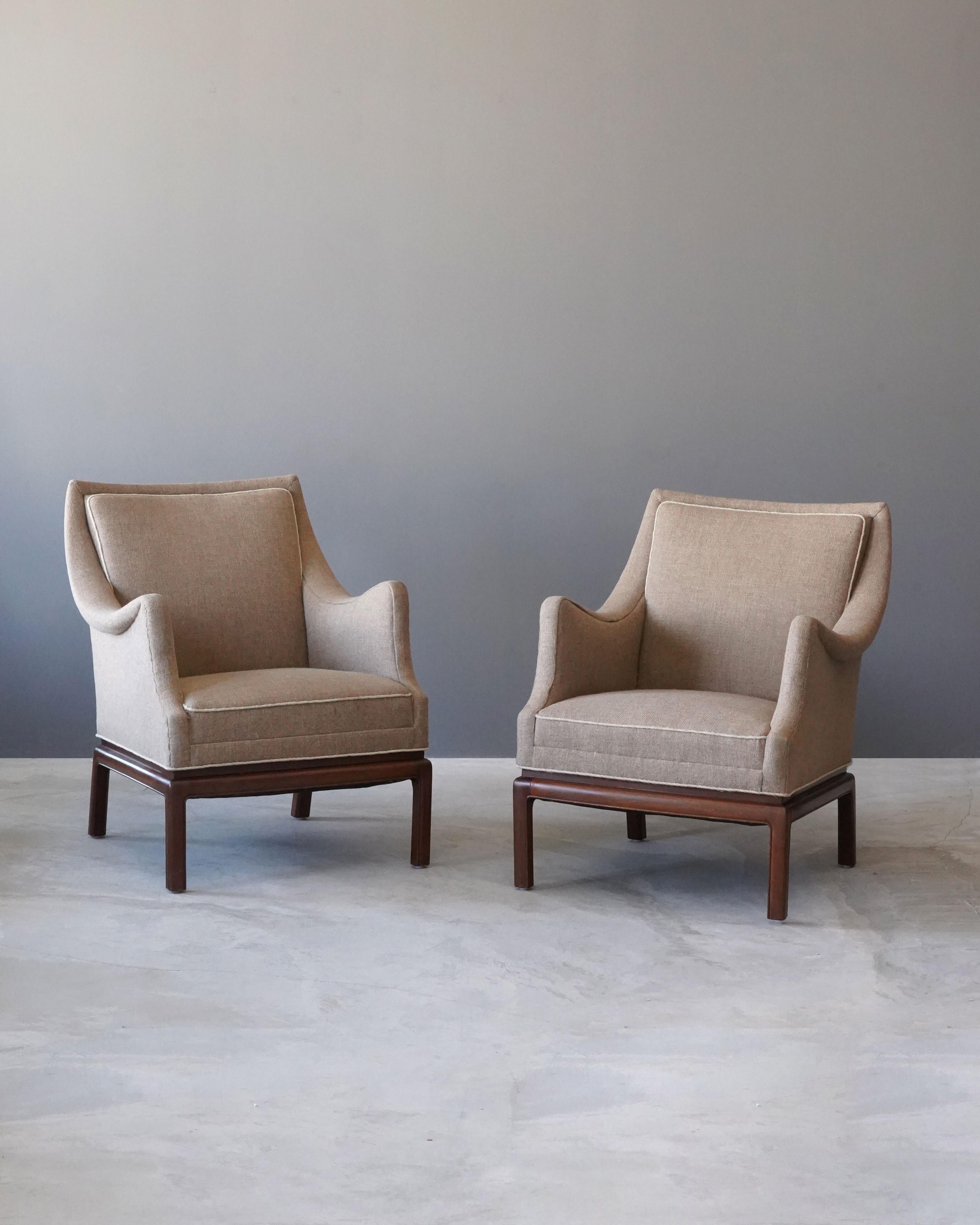 A pair of rare lounge chairs, designed by Frits Henningsen and produced in his workshop in Copenhagen, Denmark, 1940s-1950s. Henningsen was a member Copenhagen Cabinetmakers Guild.

Finely carved mahogany is paired with grey / beige fabric.