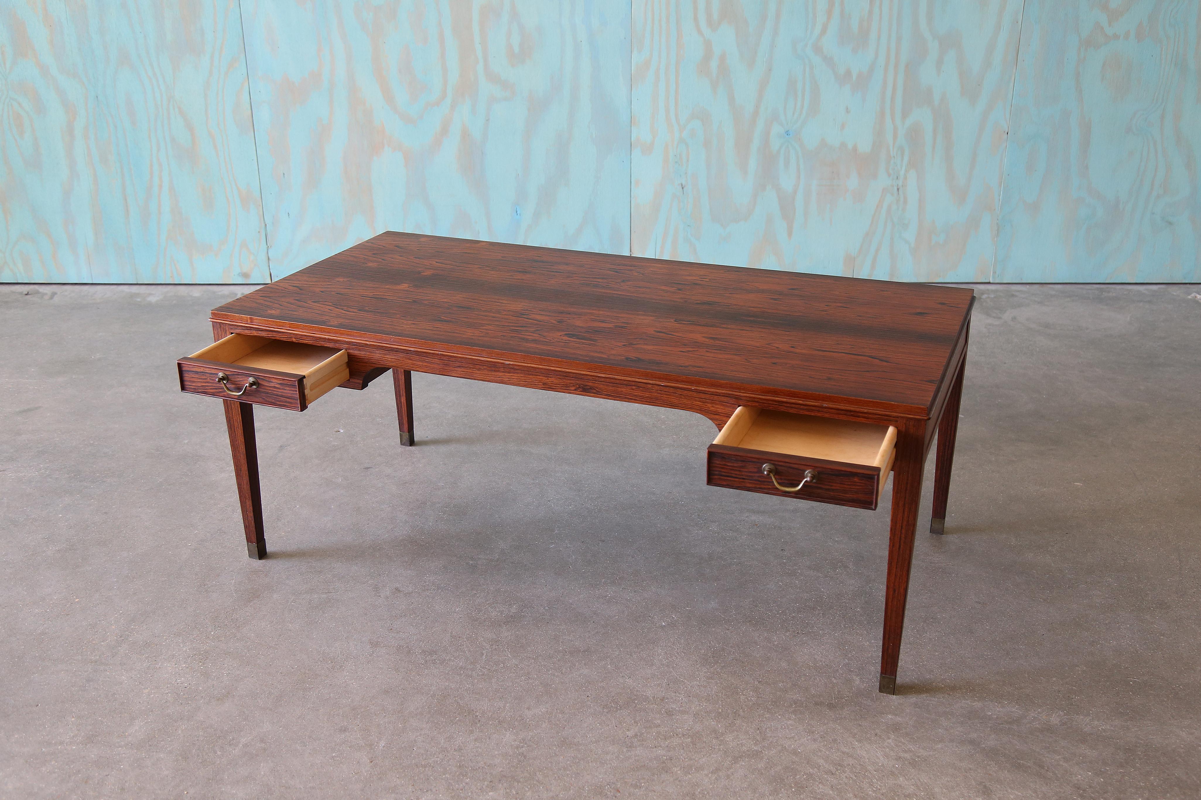 Table d'appoint en bois de rose comportant 4 tiroirs, deux de chaque côté. Les garnitures traditionnelles permettent de créer une pièce de transition qui allie les styles moderne et traditionnel danois. Conçue par Frits Henningsen, cette table peut