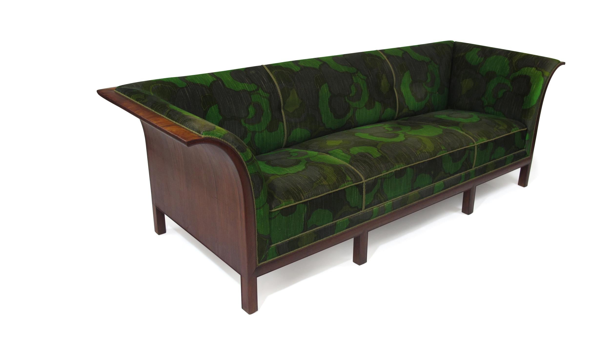 Stately sofa by Frits Henningsen, 1938, Denmark. Dramatic flared arms of flamed Cuban mahogany with eight-way hand-tied springs under seat. Reupholstered in 1960s in a green print velvet.