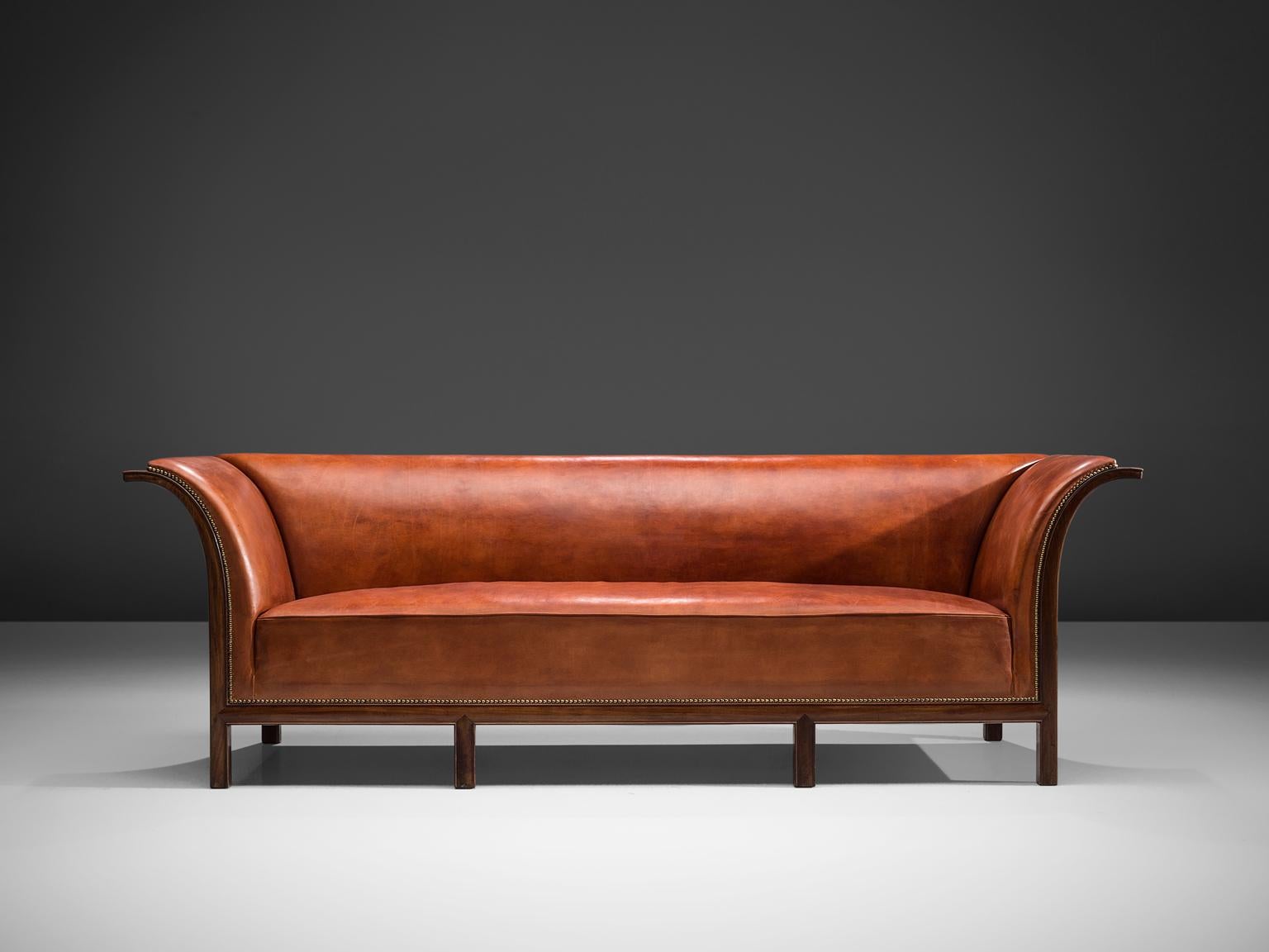 Frits Henningsen, sofa in mahogany and cognac leather, Denmark, 1930s.

This classic sofa was designed and produced by master cabinet maker Frits Henningsen around the 1930s. This gracious design is well balanced, showing an interesting contrast