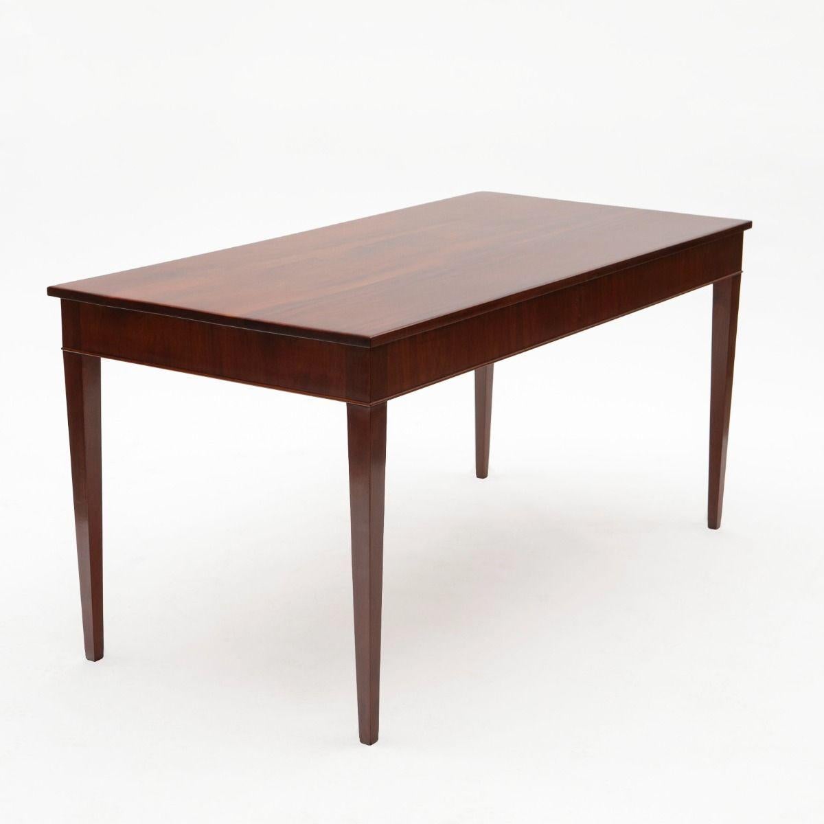 This exquisite solid Cuban mahogany writing desk, designed and crafted in the 1940s by renowned cabinetmaker Frits Henningsen, embodies the essence of mid-century elegance.
The desk features a rectangular top with a molded edge, set above three