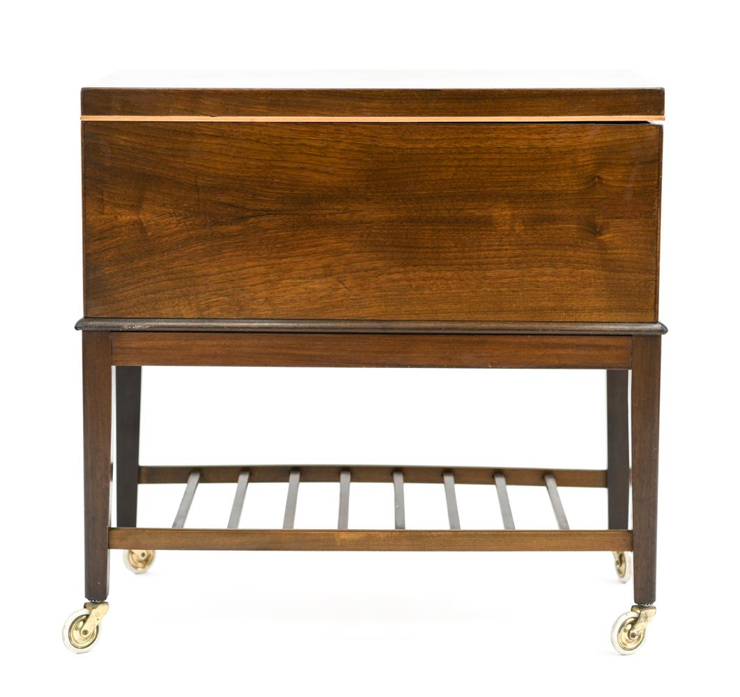 This Danish midcentury sewing box/table, circa 1950s, is in the style of Frits Henningsen. This charming, little mahogany table would be a great place for added storage in an interior. Featuring a slatted lower tier and casters for an additional