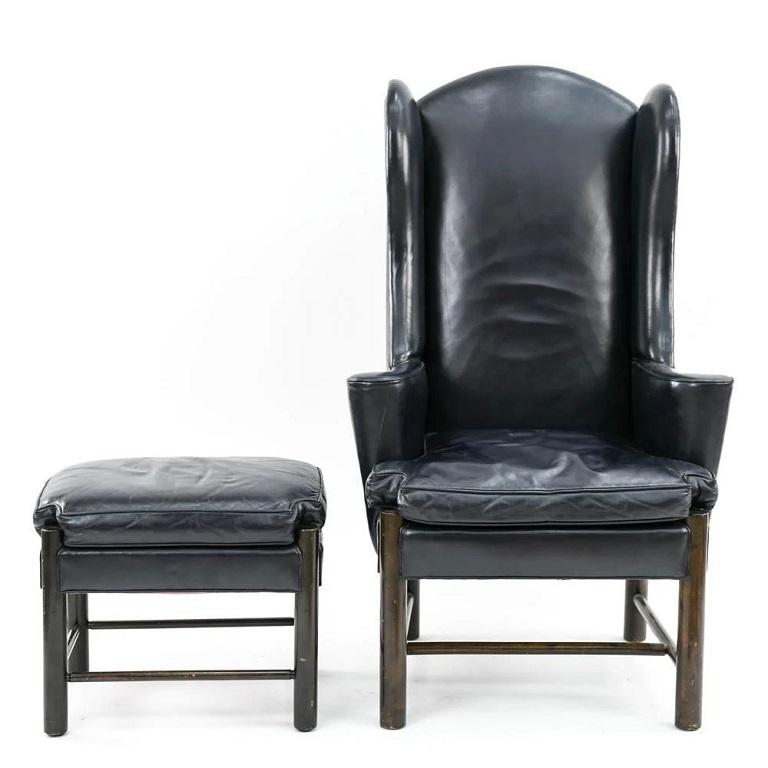 Frits Henningsen style leather wingback chair and ottoman. The chair and ottoman is dark blue leather with a wood frame. 