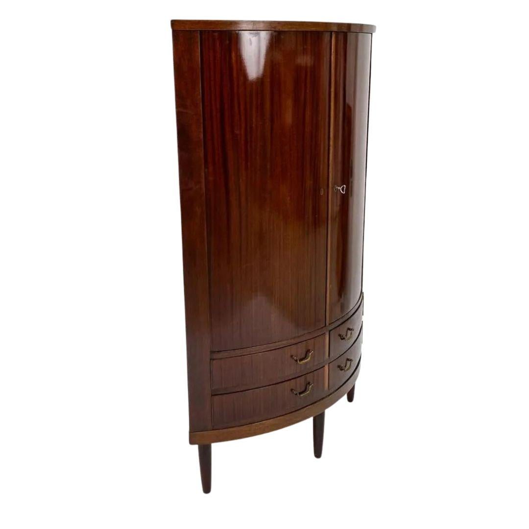 A handsome Danish mid-century corner cabinet with a rounded front, in the manner of Frits Henningsen's traditional-leaning designs c. 1960's. Including key. 

Note: Some marks to drawer interiors. Few nicks. Few small scratches. 
