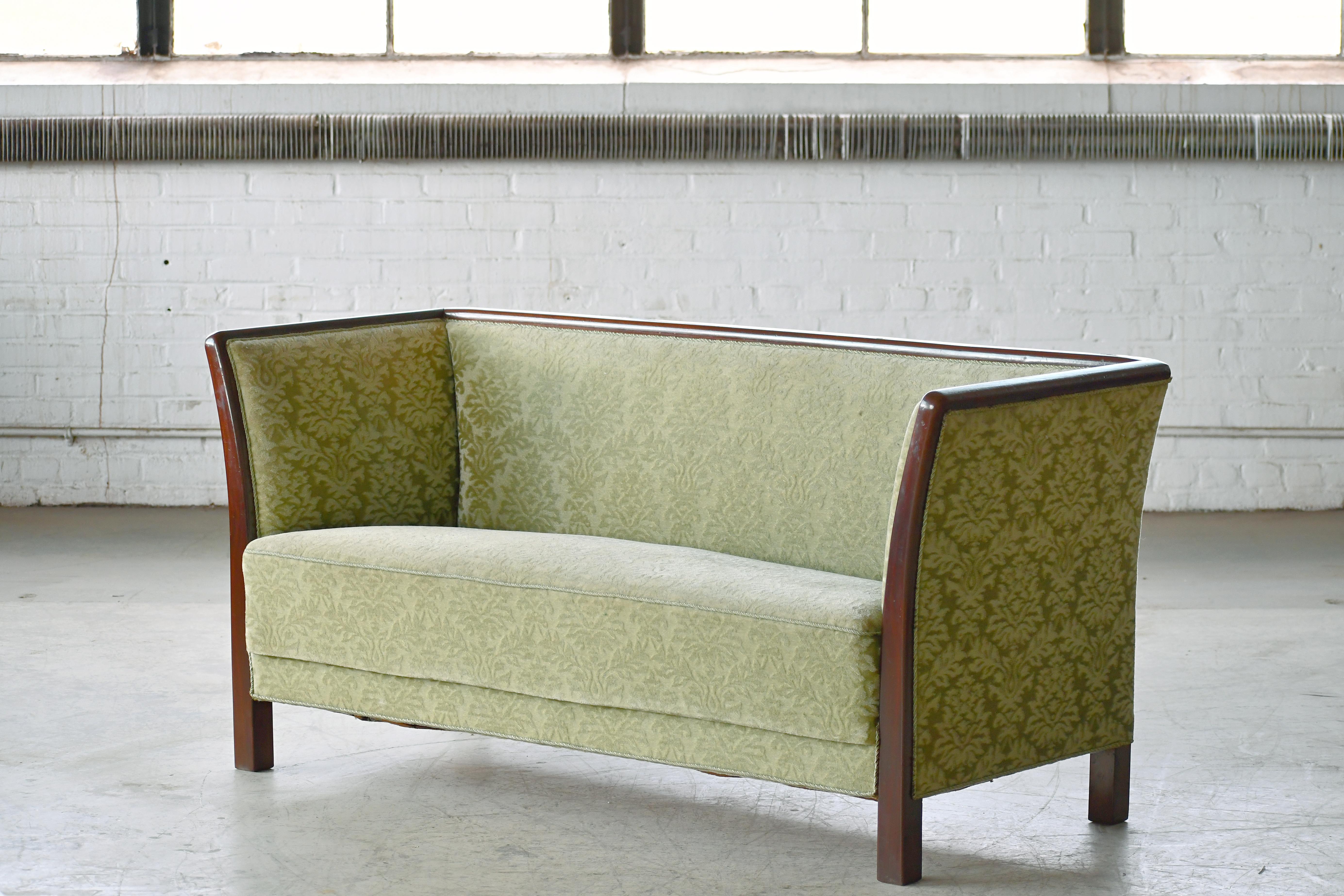 Magnifique et très élégant canapé de style Frits Henningsen fabriqué et marqué d'une étiquette par Søren Willadsen, Danemark, probablement entre les années 1940 et le début des années 1950. Encadré en acajou, le cadre se prolongeant par des pieds