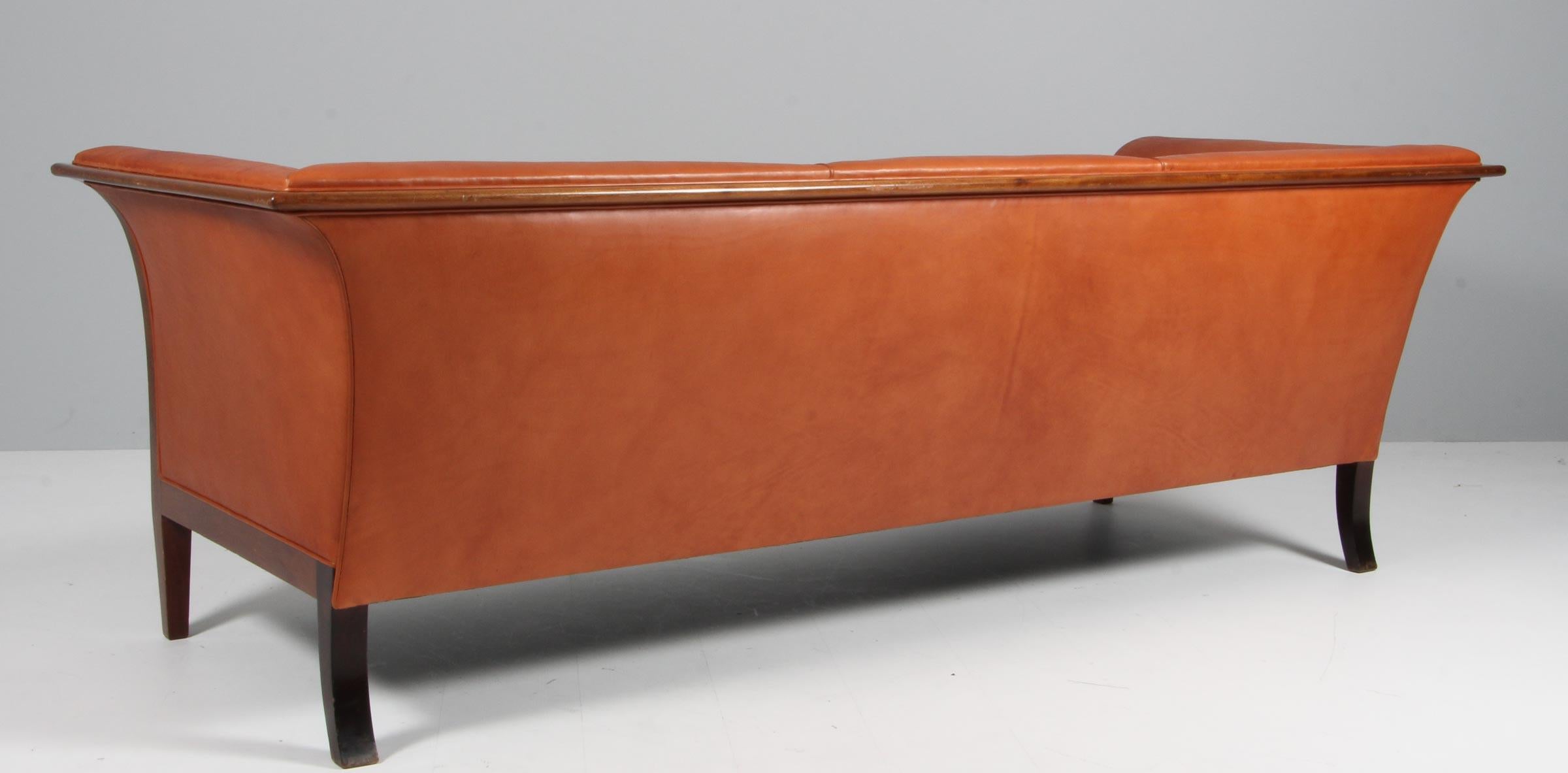 Frits Henningsen three seat sofa new upholstered with brandy coloured aniline leather

Frame of mahogany. 

Made in the 1940s. 
 