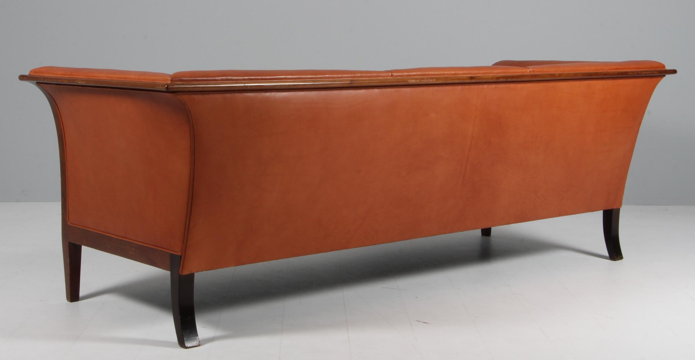 Frits Henningsen three seat sofa new upholstered with brandy coloured aniline leather

Frame of mahogany. 

Made in the 1940s. 
 