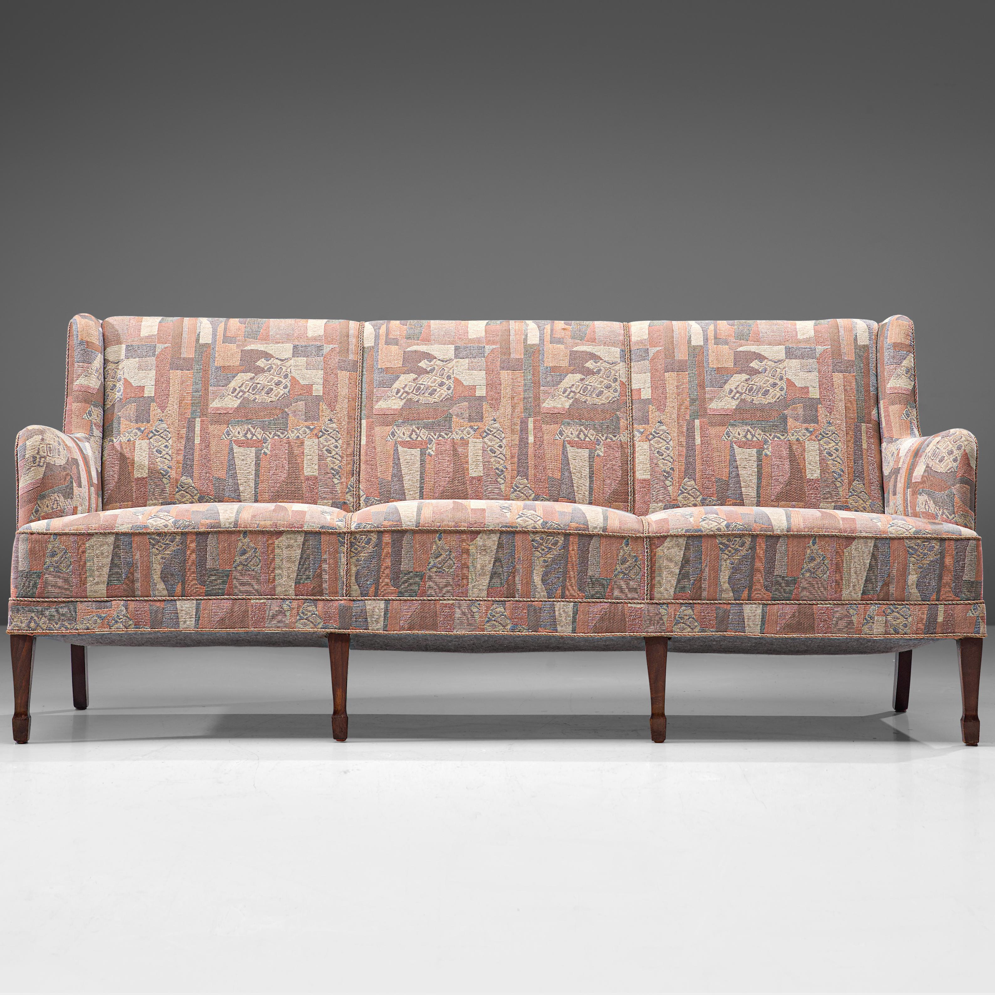 Frits Henningsen, three-seat sofa, fabric and oak, Denmark, 1940s. 

This elegant three-seat sofa is made by master cabinetmaker Frits Henningsen. This refined sofa is a classic piece. The backrest holds small wings, which runs over into the