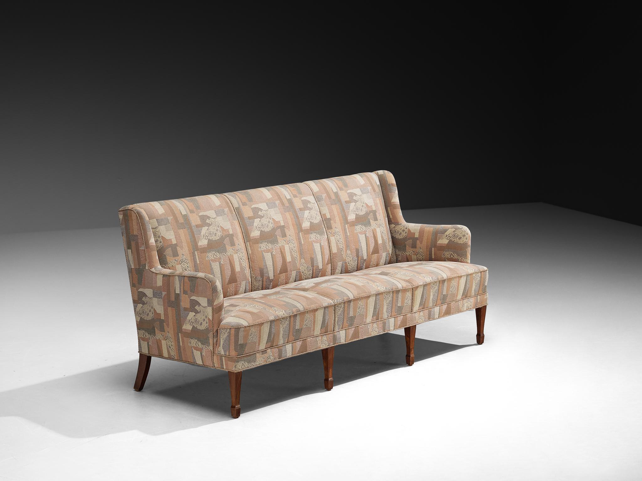 Frits Henningsen, dreisitziges Sofa, Stoff und Buche, Dänemark, 1940er Jahre. 

Dieses Sofa, das Frits Henningsen in den 1940er Jahren entwarf, zeigt eine raffinierte Balance zwischen traditioneller Handwerkskunst und moderner Zurückhaltung. Seine