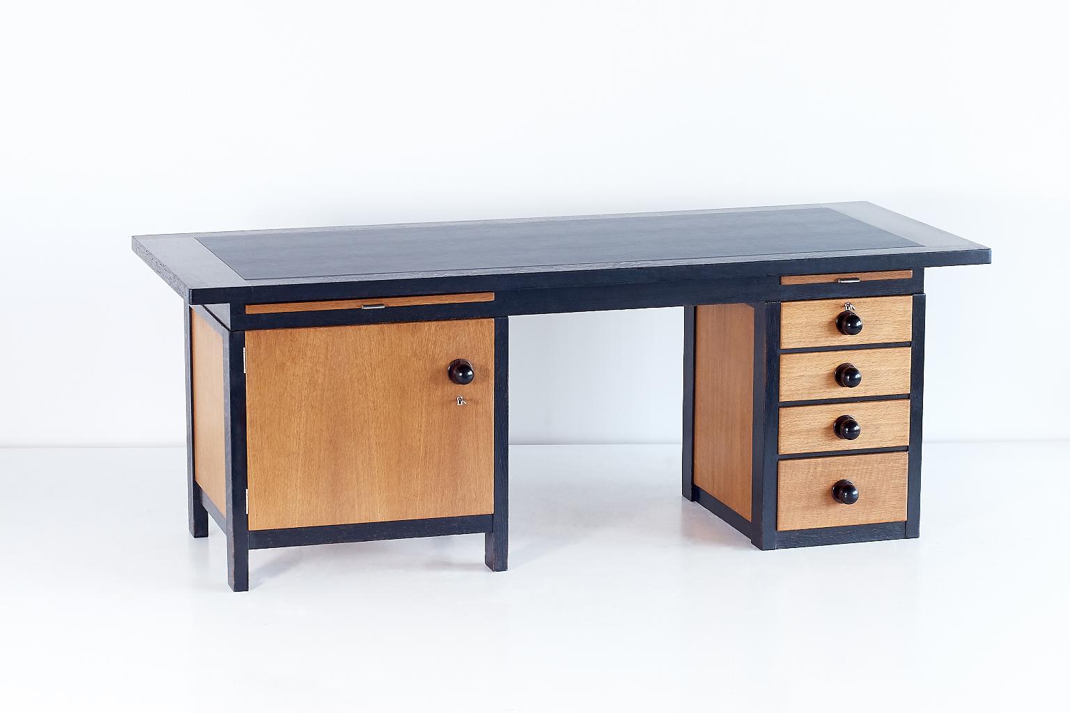 This unique architect's desk was designed by Frits Spanjaard in 1932. With its generous proportions, striking asymmetry, contrasting woods and the large knobs in solid Macassar ebony, the desk can be considered as an important example of the Haagse