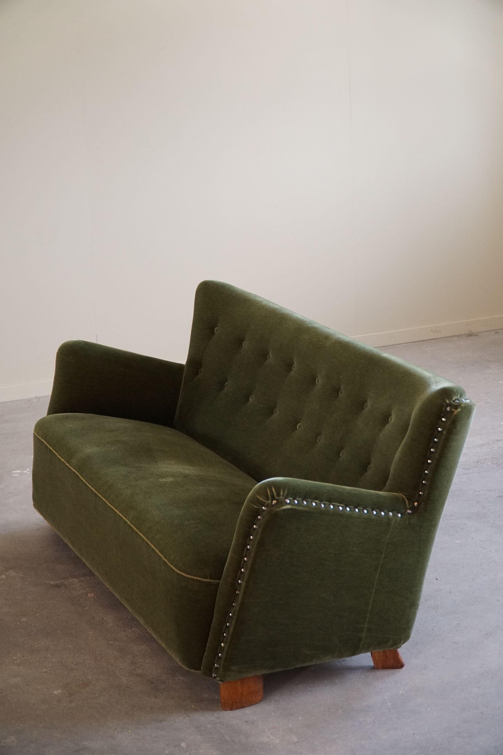 Ce magnifique canapé trois places en velours vert d'origine incarne le design danois Mid Century Modern des années 1940. Son revêtement en velours vert luxuriant respire le luxe et le confort, tandis que les pieds en chêne assurent la stabilité et