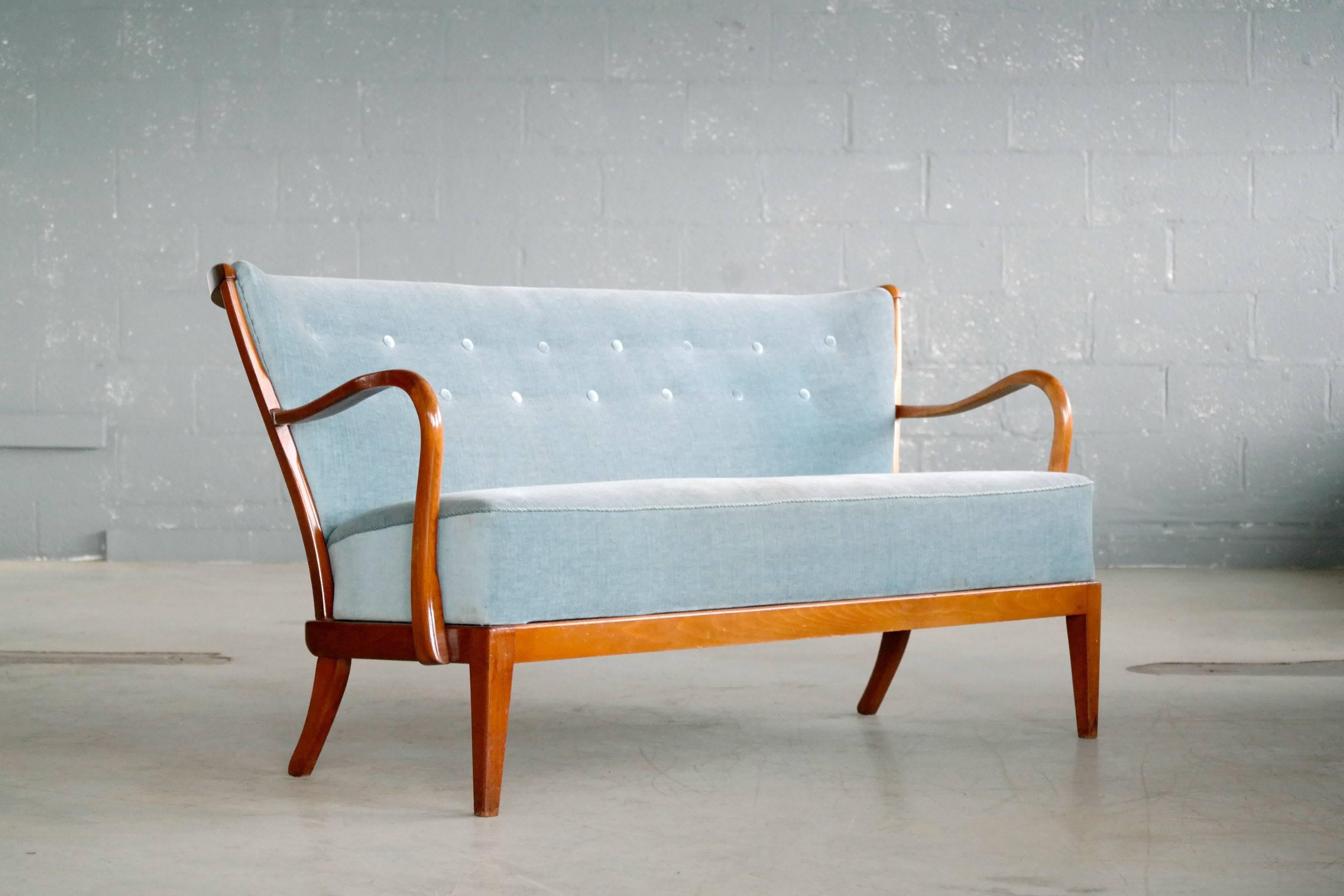 Fantastic 1940s Fritz Hansen attributed sofa in the company's characteristic style of open armrests and spindle back. Beautiful refined lines with curving arms, spring seating and tufted back. Some wear to the lacquer mainly on the armrests that we