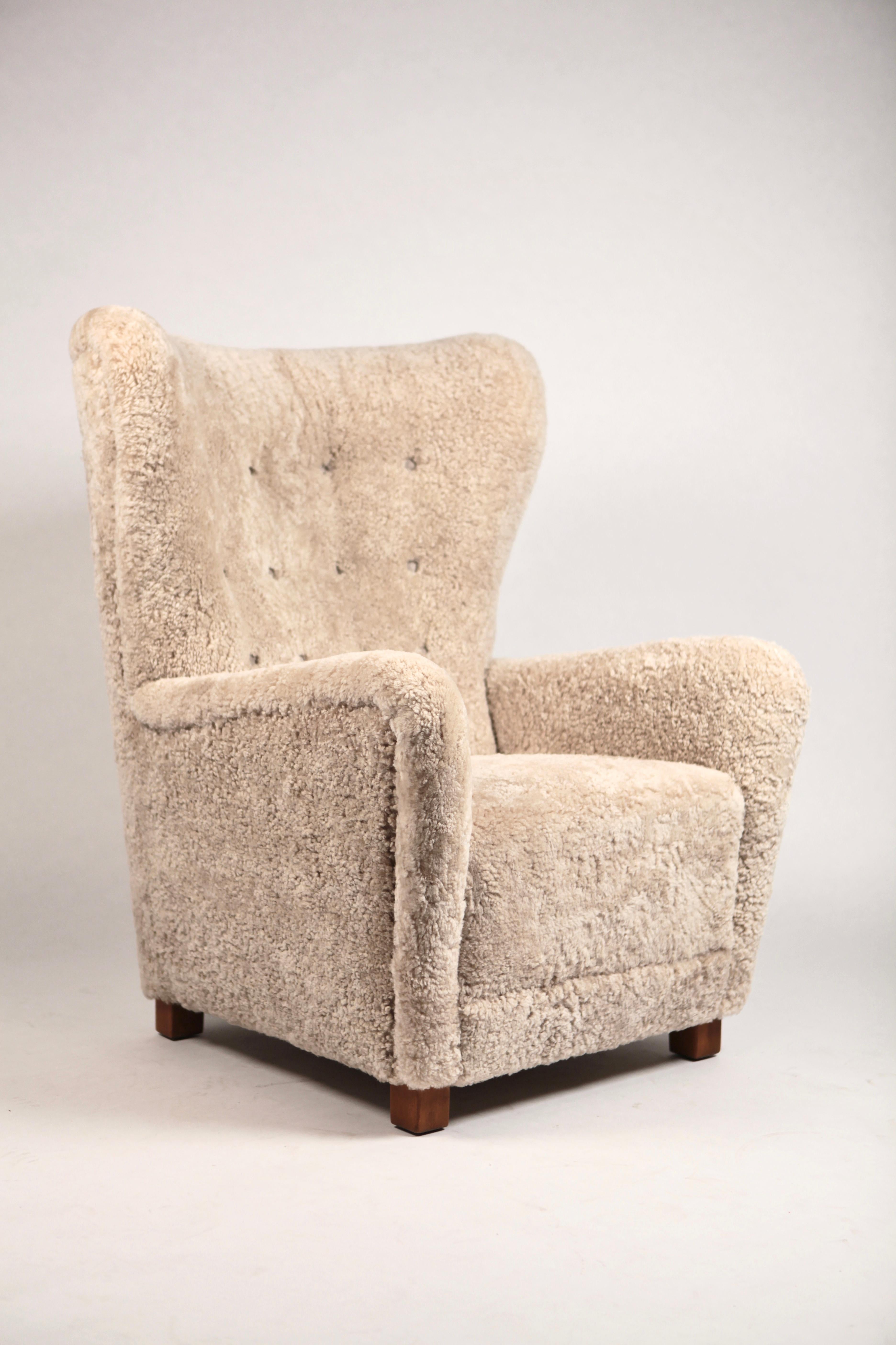 Large high wing back easy chair by Fritz Hansen, model 1672, executed in Denmark, 1940s.
New reupholstered in New Zealand shearling, deep fitted leather buttons, stained oak legs.
Excellent condition.