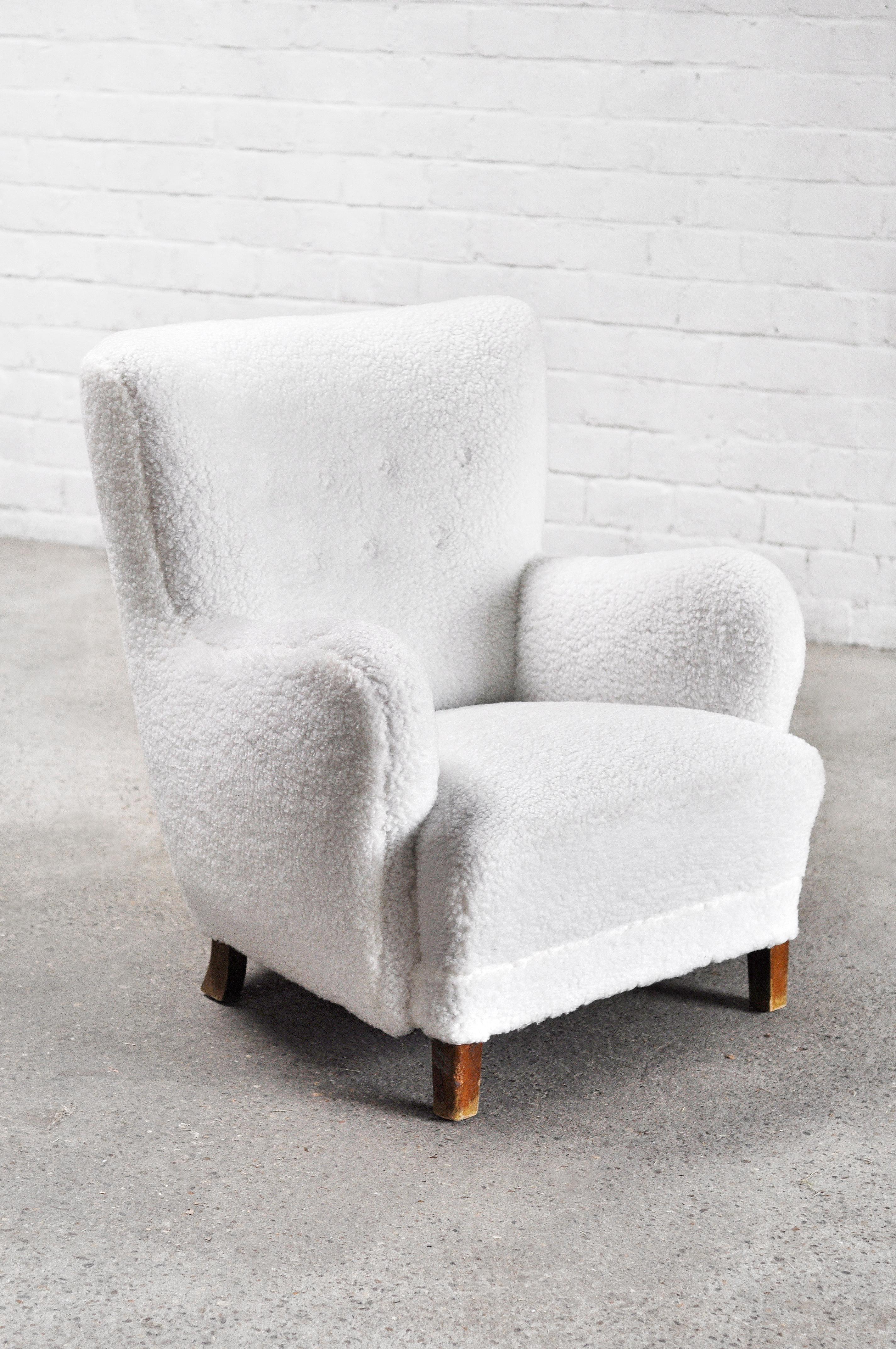 Iconic easy chair made by Fritz Hansen in the 1940's or early 1950's. This model is rarely seen and one of the 1669 variants. It was newly upholstered in a shearling white wool and has sculptural legs of stained beech. Sits very