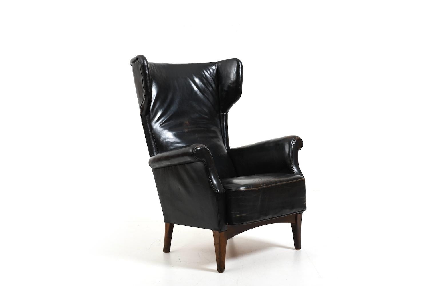 Fritz Hansen, model 8023 wingback lounge chair. Original patinated black leather and oak base. In absolutely untouched condition. 1940s/50s.