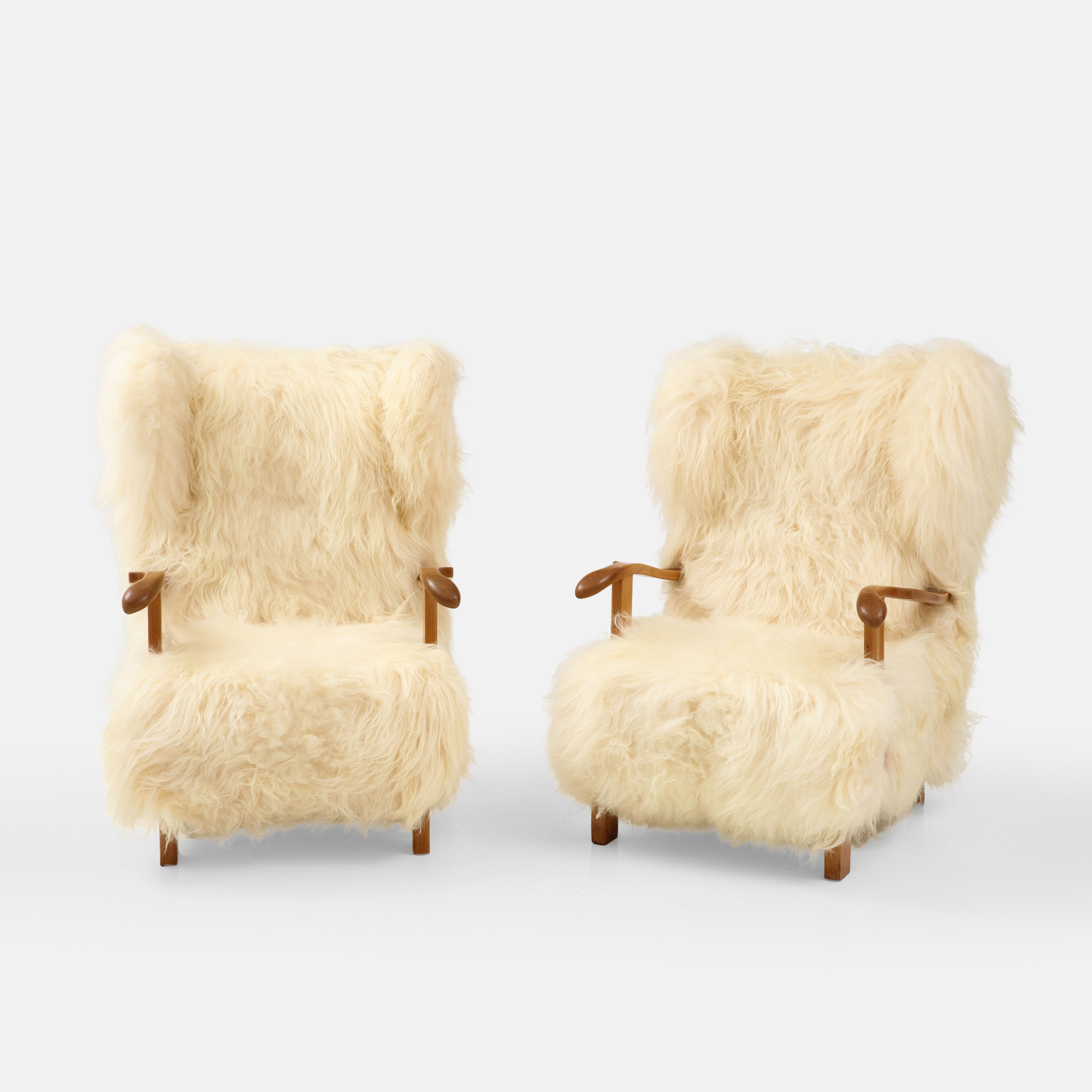 Fritz Hansen rare pair of large wingback lounge chairs model 1582 with beech wood frame and luxurious sheepskin upholstery, Denmark, 1930s.  These incredibly chic early Danish period armchairs or easy chairs have generous proportions throughout