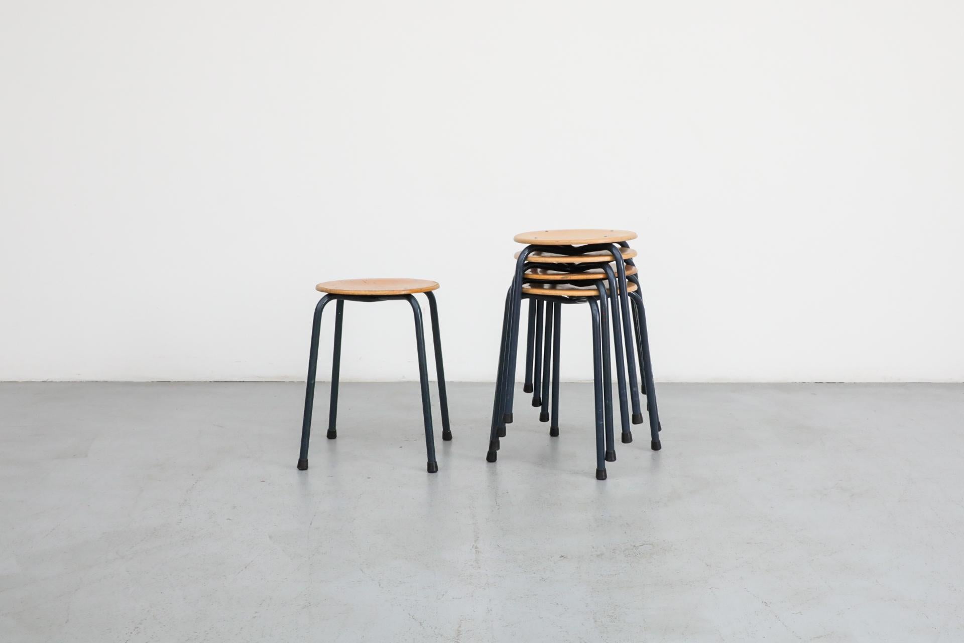 Fritz Hansen style industrial task stools with blue enameled metal frames and blonde wood seats. In original condition with visible wear and patina consistent with age and use. Sold individually.