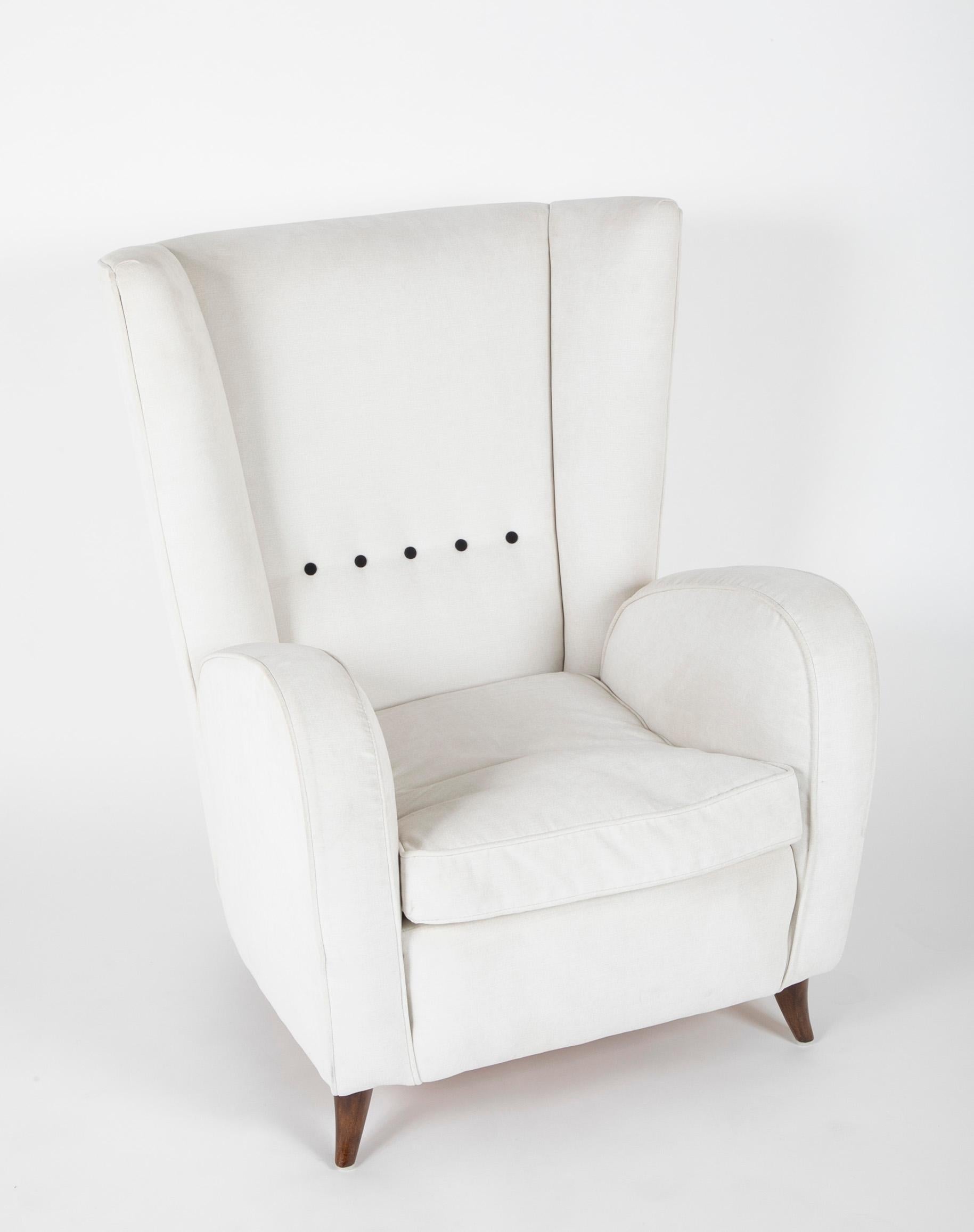 A Fritz Hansen wingback chair upholstered in white fabric having four black buttons.