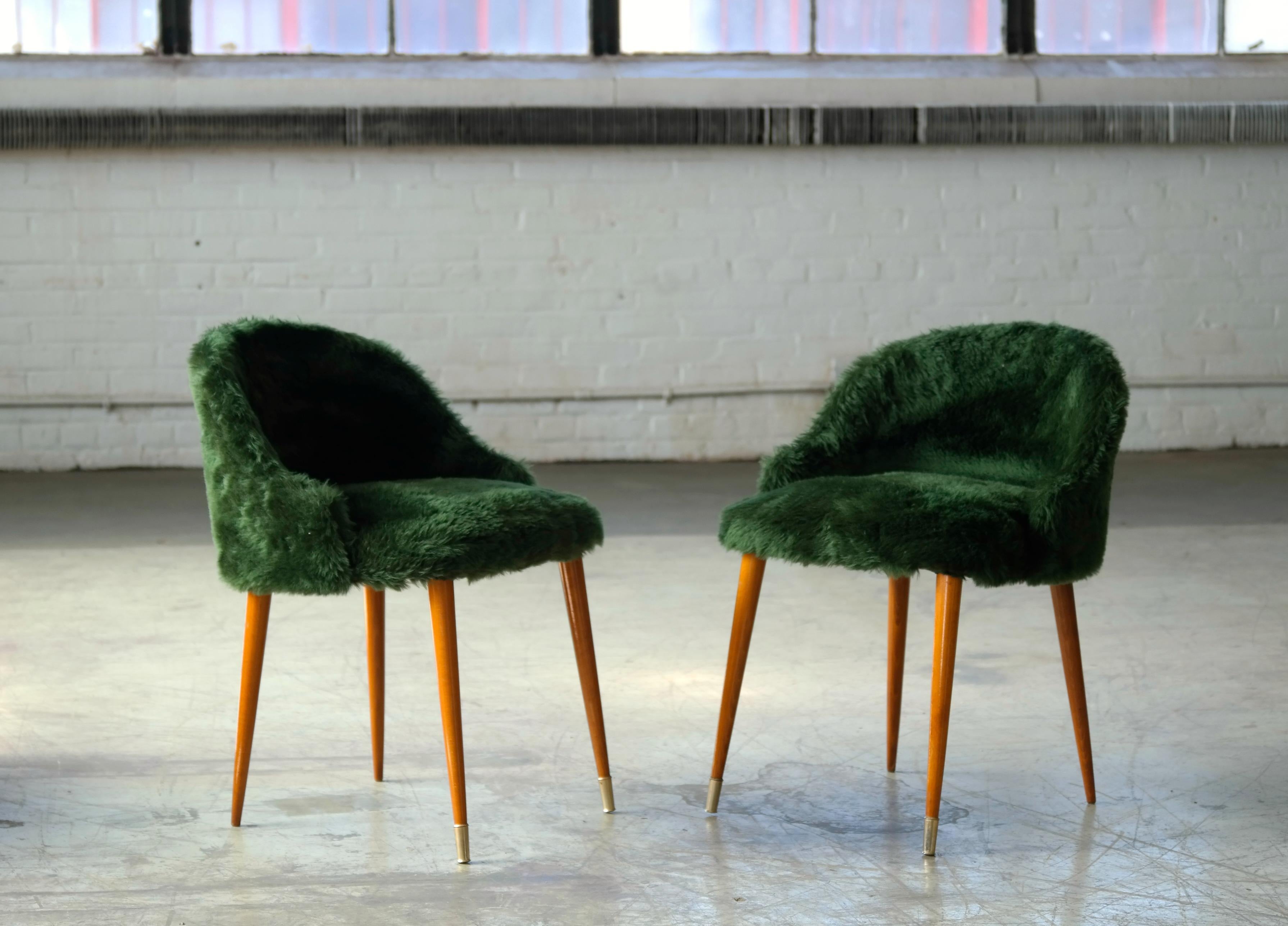 Very elegant and charming pair of vanity chairs in the style of Frode Holm. Elm wood legs with brass shoes on the front and seats covered in green faux fur. Light design but sturdy and comfortable. Near mint condition. The pair is unmarked with age