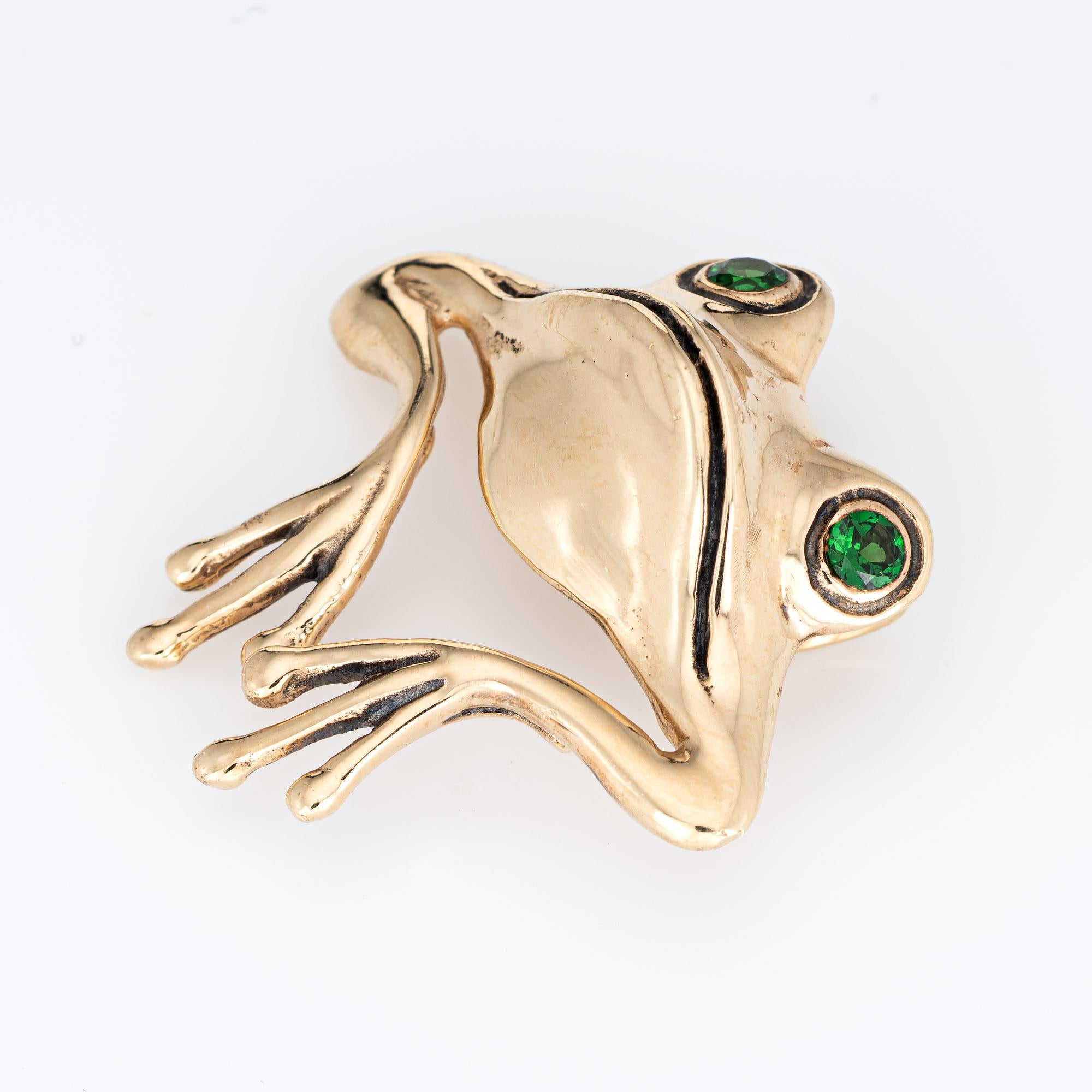 Finely detailed vintage frog pendant crafted in 14k yellow gold (circa 1960s to 1970s).  

Two estimated 0.10 carat tsavorite garnets are set into the eyes (0.20 carats total estimated weight). 

The charming & whimsical frog sits perched with