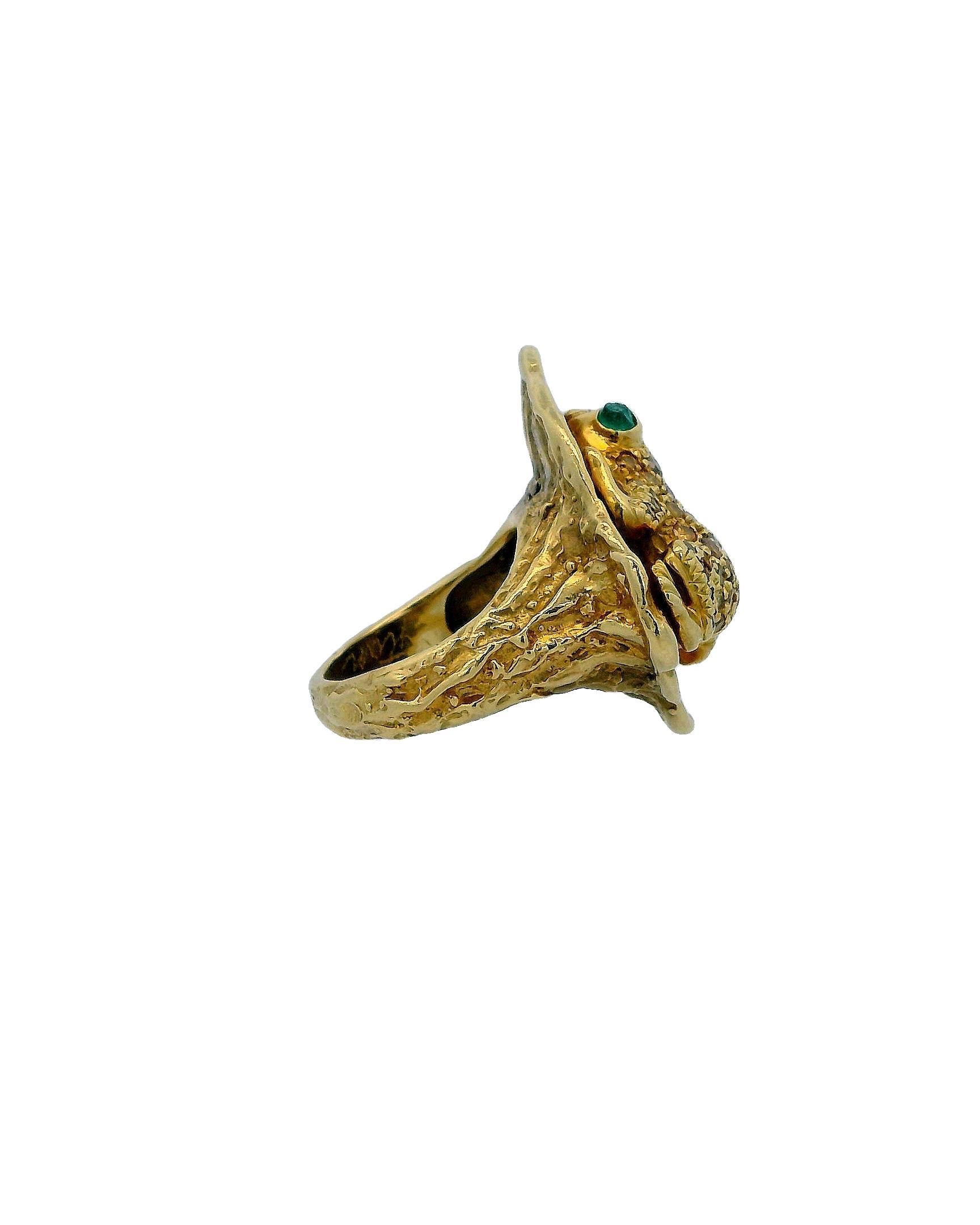 Eine skurrile Mischung aus Natur und Kunsthandwerk.

Dieser auffällige Ring zeigt einen sorgfältig gearbeiteten Frosch, der auf einem strukturierten Goldband thront. Der Körper des Frosches ist mit komplizierten Details verziert, die das Wesen
