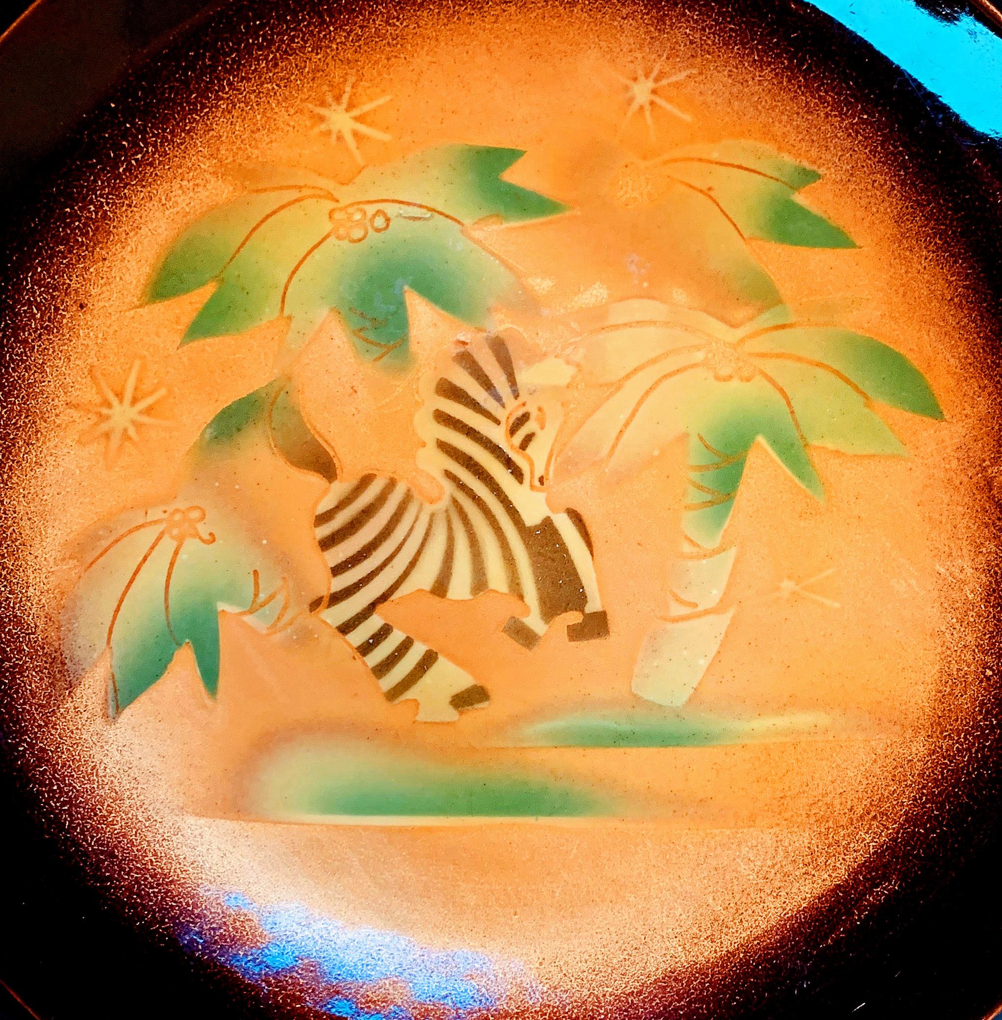 Suffused with brilliant tangerine and jade tones and featuring an exuberant, Art Deco zebra cavorting amidst a group of coconut palms, this brilliant example of American enamel artistry was created by Edward Winter, one of the nation's pioneering