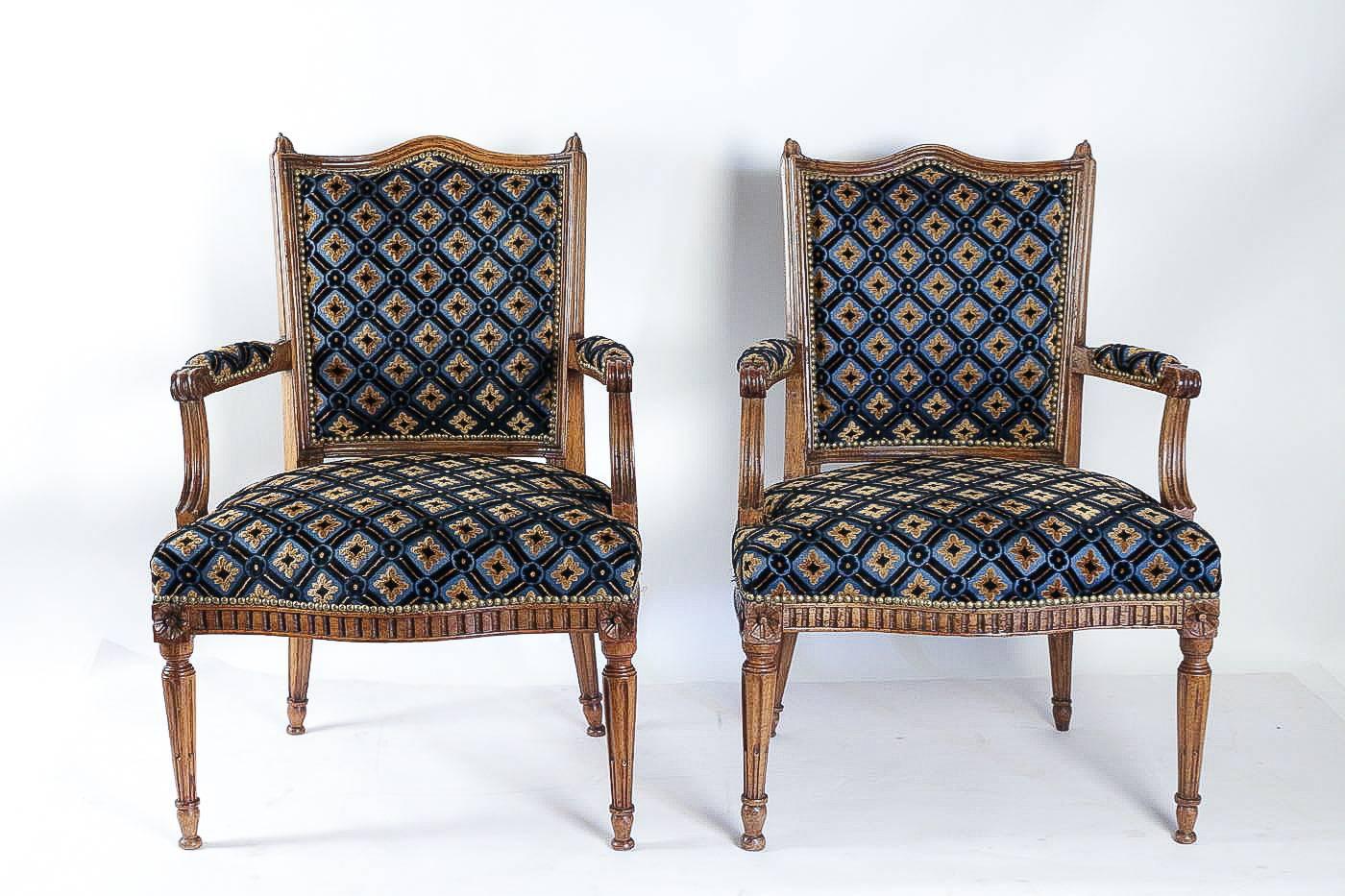 A rare and unique pair of armchairs in hand carved walnut, flower buds and serpentine fronted seat raised on fluted legs.

Elegance and magnificent mastery of the art of the seat in this early-Louis XVI period pair of armchairs. The quality and
