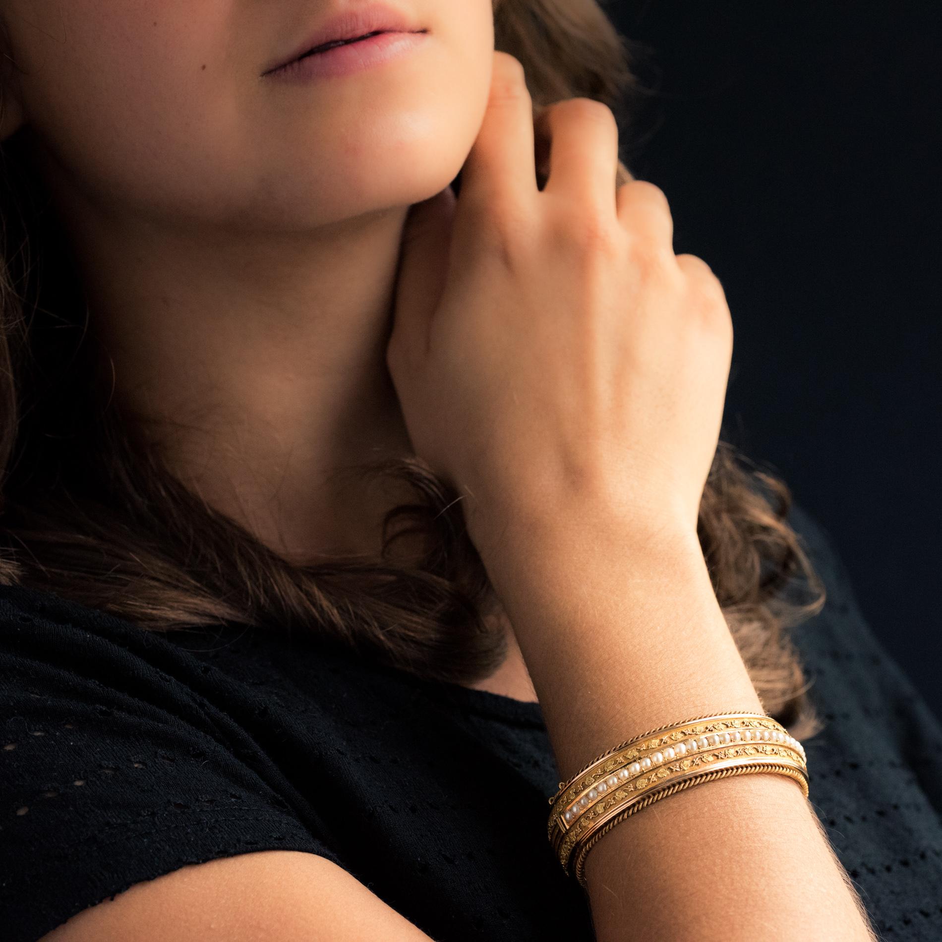 Bracelet in 18 karat rose and yellow gold, rhinoceros head and eagle's head hallmarks.
Large oval bangle bracelet, it is adorned on the top with a line of natural pearls accompanied on both sides but going all the way around, with an ivy stem. The