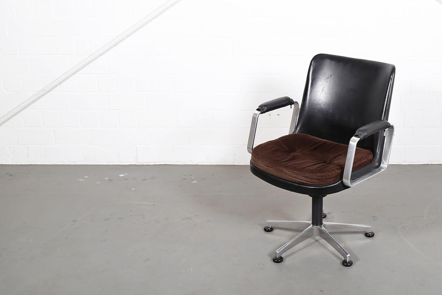 Fröscher “Elizabeth” office chair / conference chair designed by Ib Kofod Larsen (attributed) in a modern Danish design. The backrest is probably covered with black synthetic leather and the seat cushion with a brown cord fabric. Padded armrests.