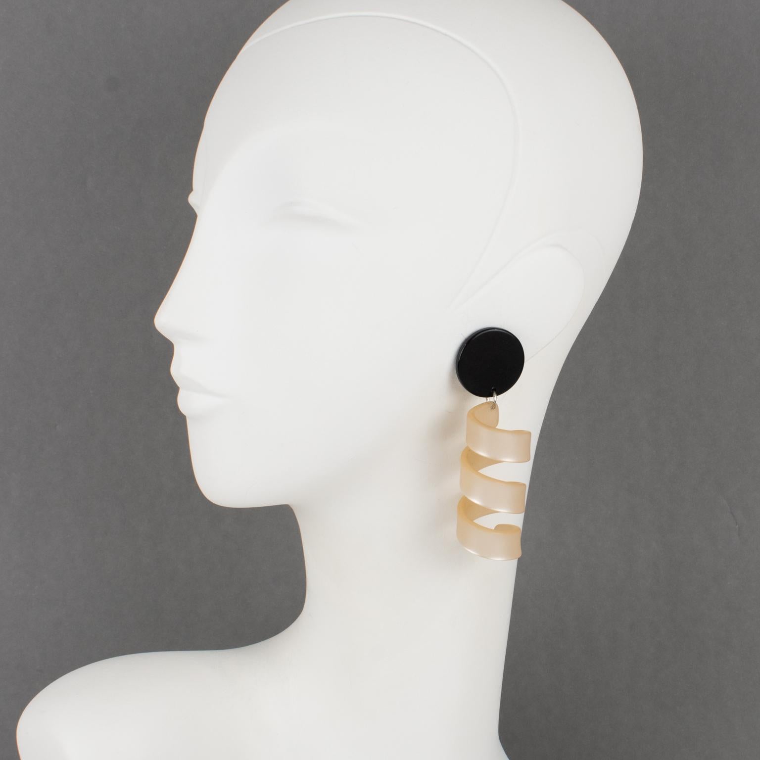 These stunning oversized carved Lucite clip-on earrings feature a dimensional coiled shape element in frosted beige nude color contrasted with a black fastening disk. There is no visible maker's mark.
Measurements: 1 in wide (2.5 cm) x 3.38 in high