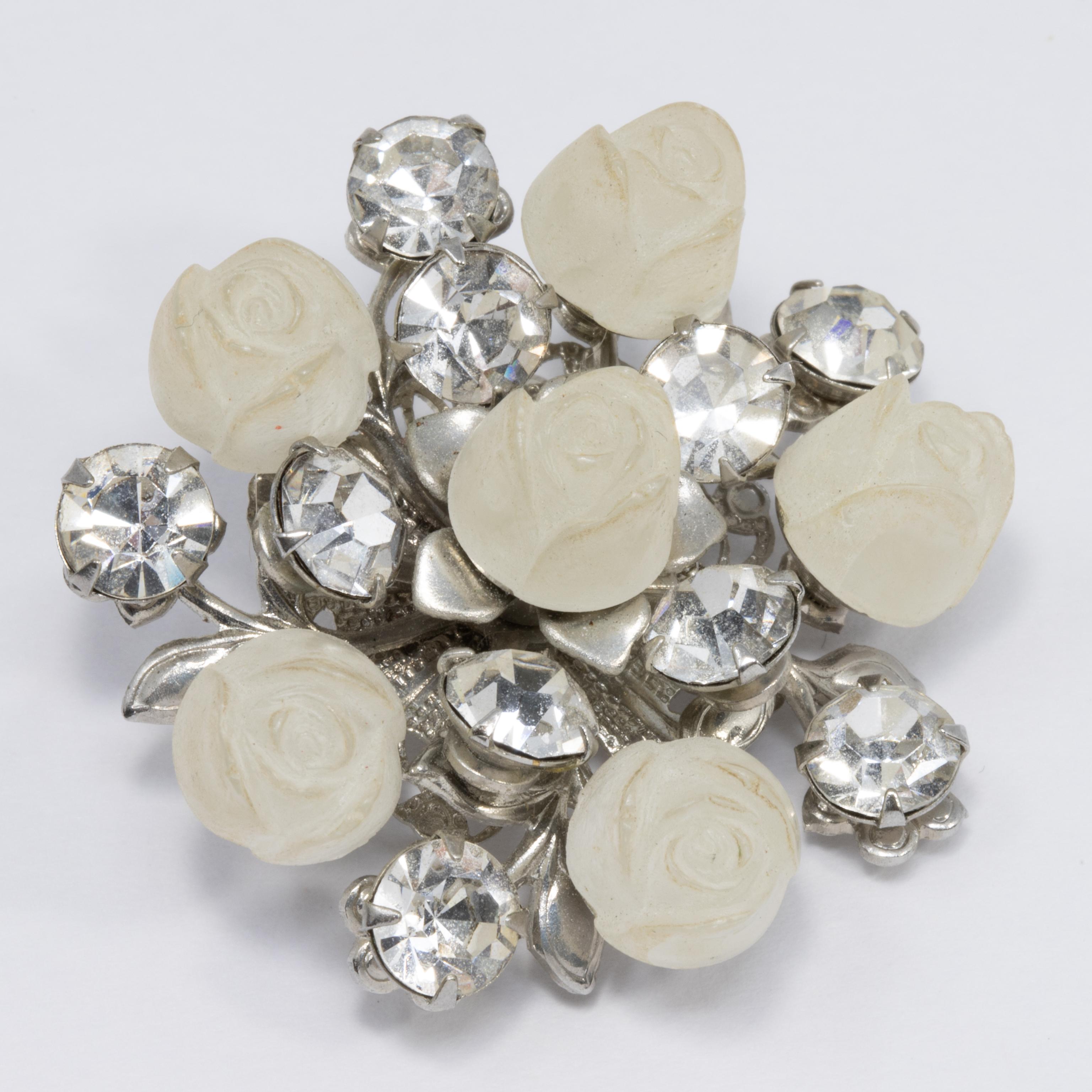 Exquisite carved frosted white roses accented with crystals, set in a floral-themed silvertone metal setting. A delightful vintage pin!
