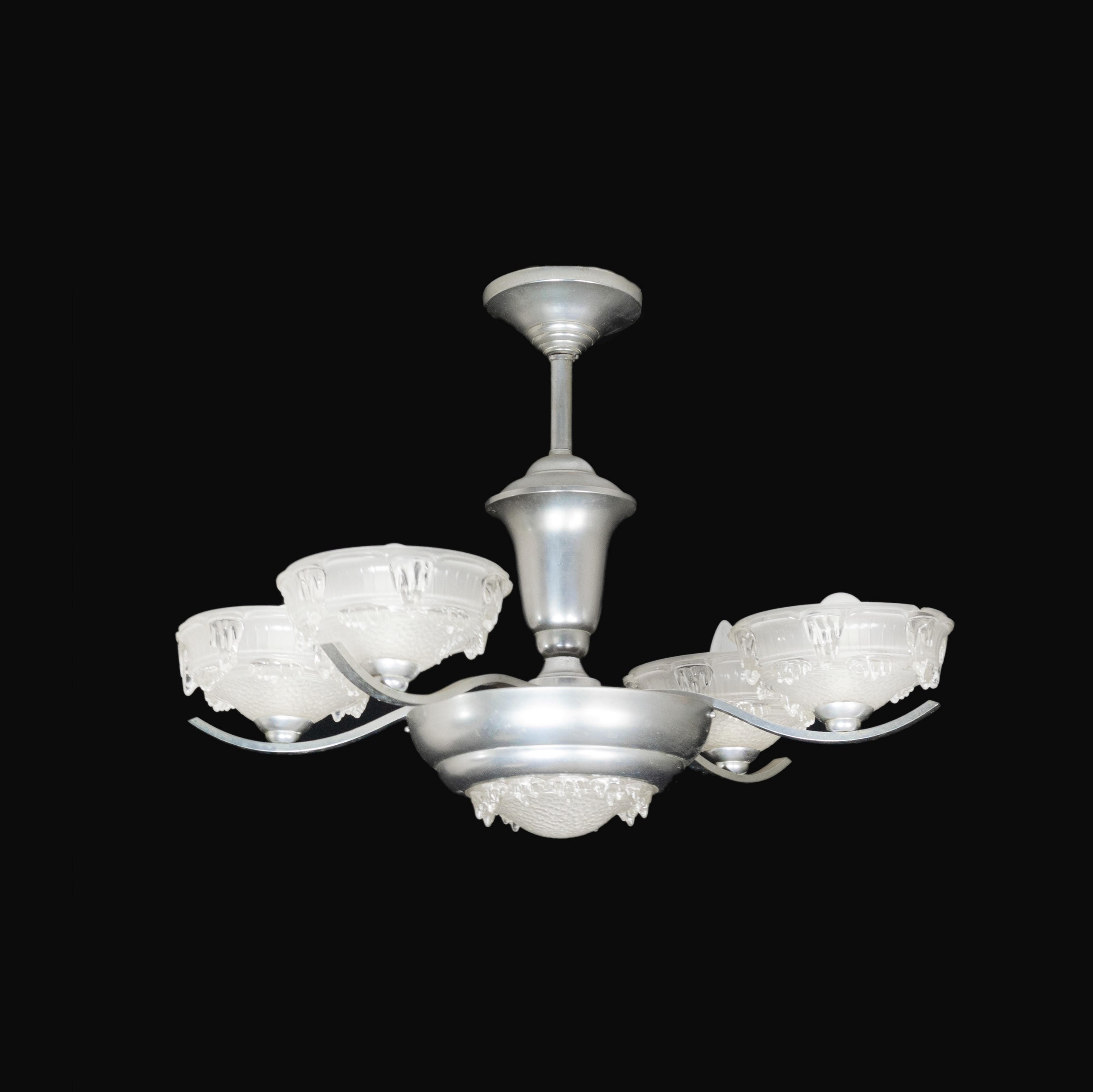 An Art Deco bistro chromed color four arms chandelier with frosted glass.  
Good. Reviewed recently and in working conditions.  

The chandelier is currently wired for both European Union and US standards LED lights. The LED lamp bulbs you see in