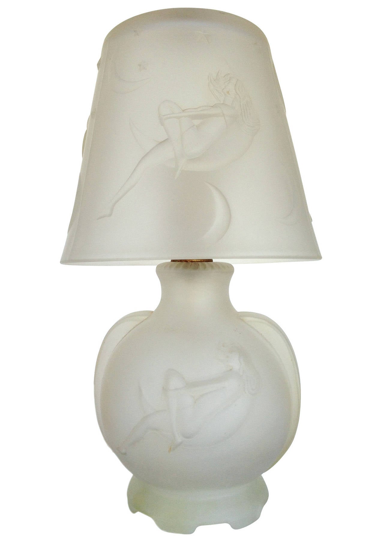 This frosted glass boudoir lamp features a nude woman gazing at the stars inside a crescent moon, made circa 1920. This portrait can be seen along the shade and lamp body in a repeating pattern.

The lamp features a nice Art Deco accent along the