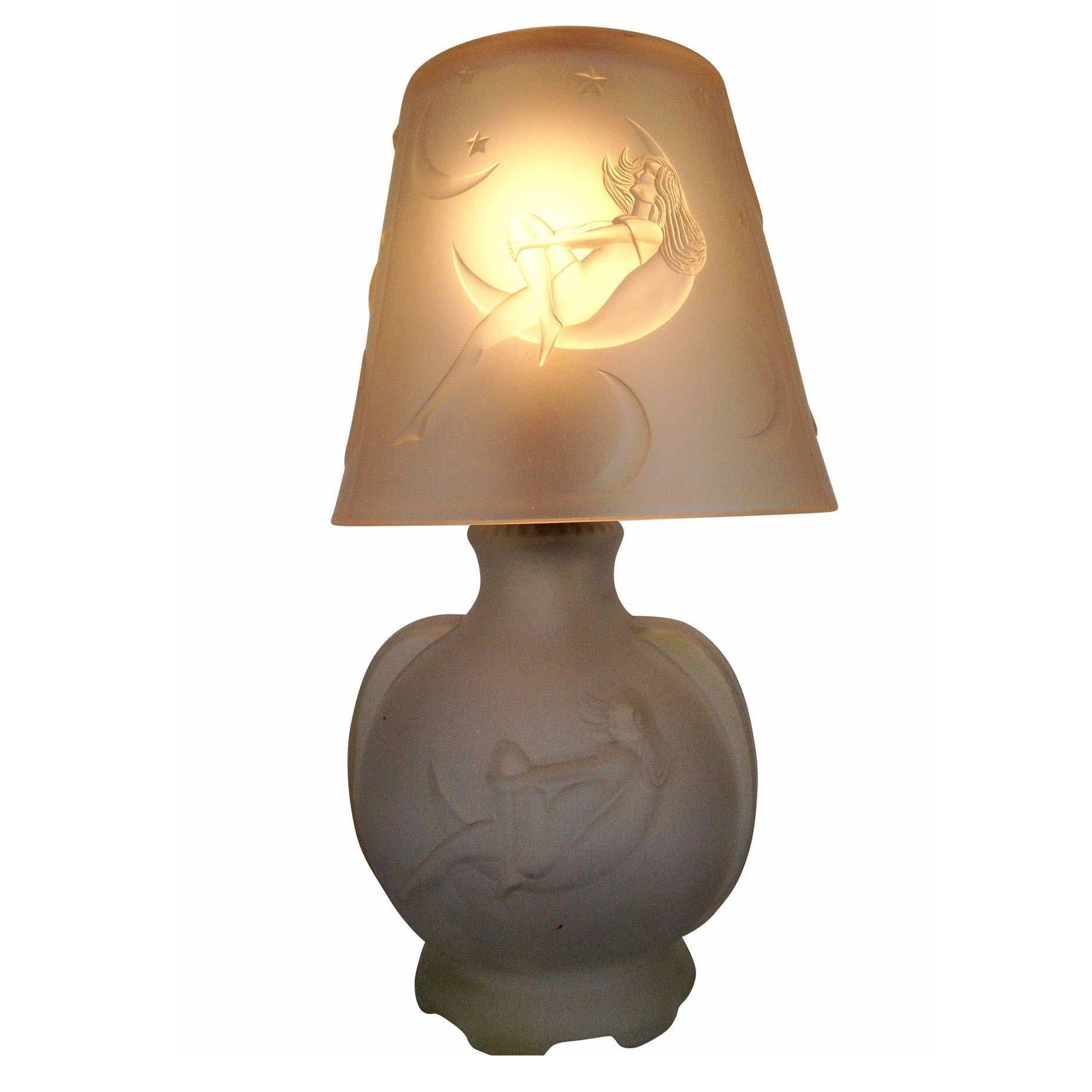 This frosted glass boudoir lamp features a nude woman gazing at the stars inside a crescent moon, made circa 1920. This portrait can be seen along the shade and lamp body in a repeating pattern.

The lamp features a nice Art Deco accent along the