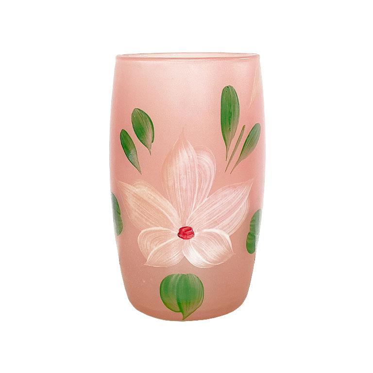 A set of 8 frosted pink drinking glasses handpainted with a white floral motif. Each cup features a hand-painted white flower (perhaps a Magnolia.) with large outstretched petals. Lush green leaves surround it on either side of the bloom. The