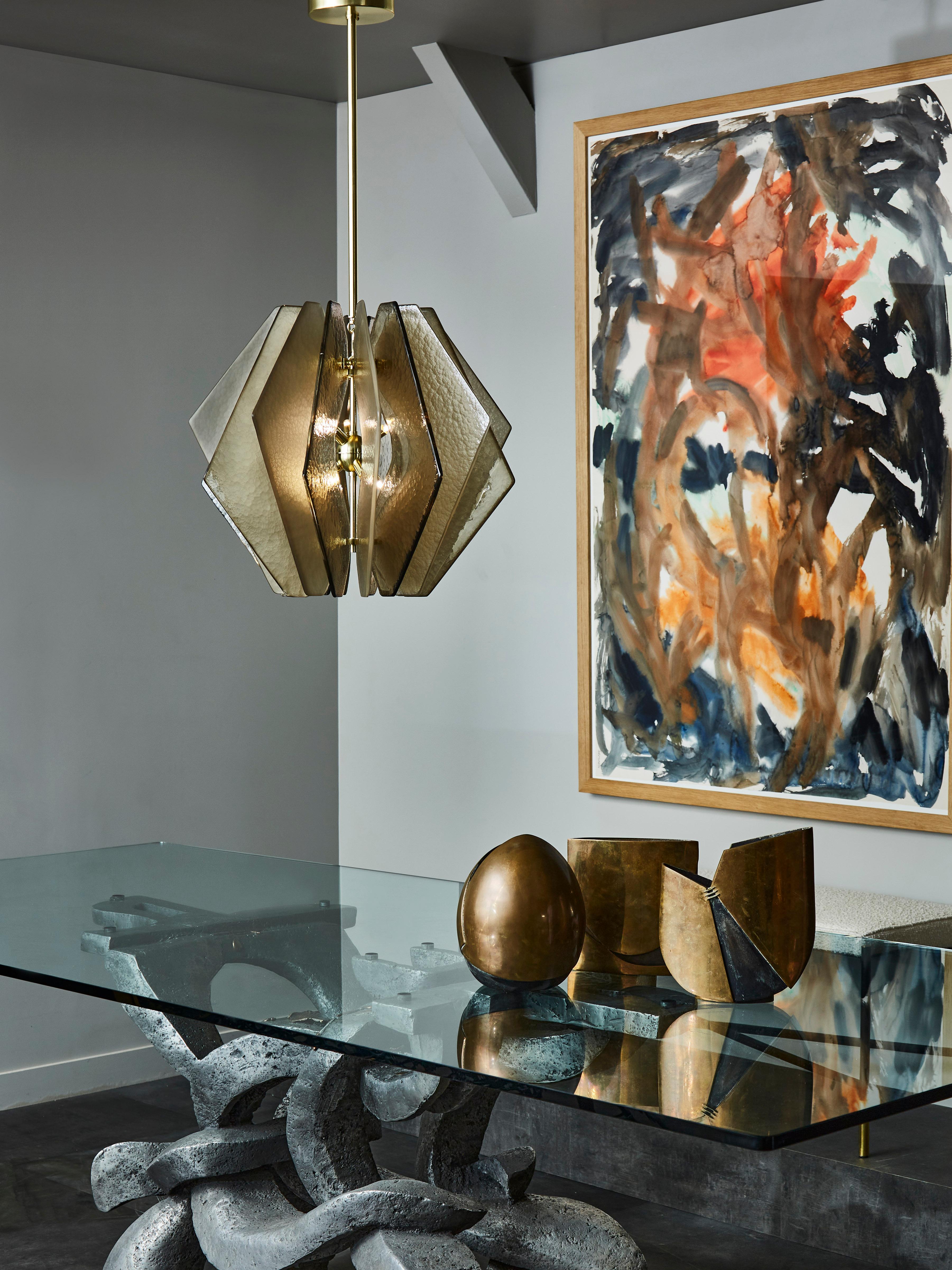 Satin brass suspension with decorative and asymmetrical glass slabs placed all around the central structure.

The slabs are made of frosted murano glass tinted in two different shades bronze.

Six lights per suspension.
