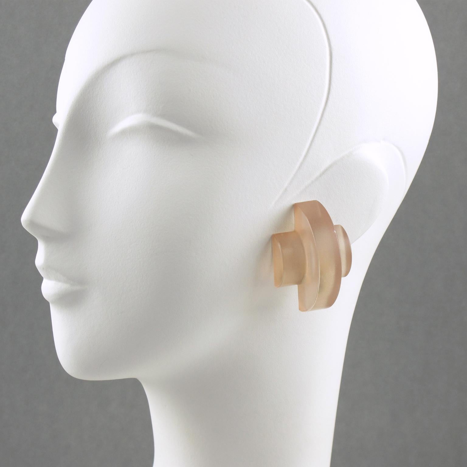 These impressive carved Lucite clip-on earrings feature a dimensional geometric shape in frosted light pink nude color. There is no visible maker's mark.
Measurements: 1.19 in. wide (3 cm) x 1.75 in. high (4.5 cm) x 0.88 in. deep (2.2 cm).