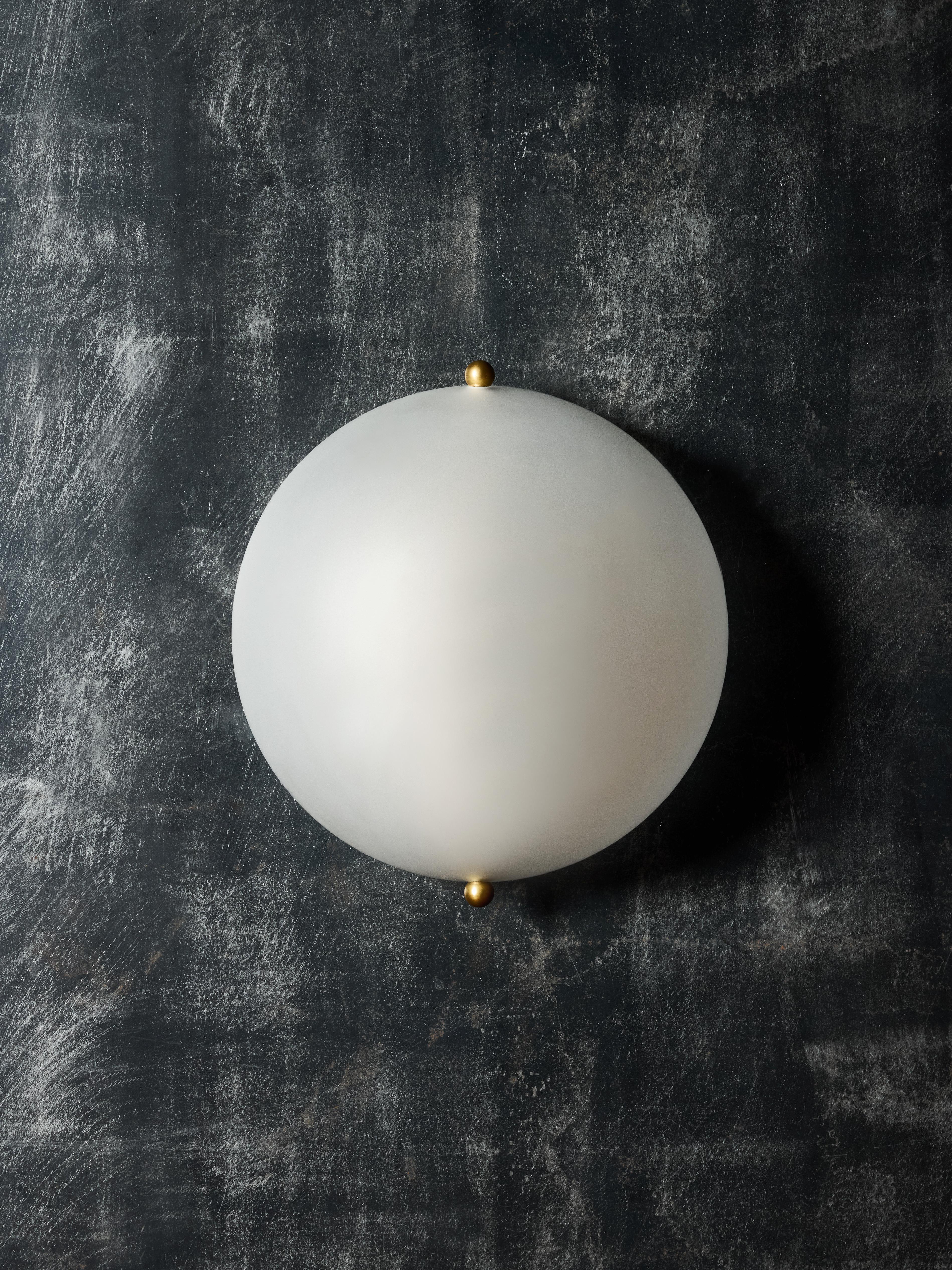 Elegant wall sconces feature a frosted glass half-sphere, beautifully diffusing the light from a single source. The glass is attached with two decorative brass screws.