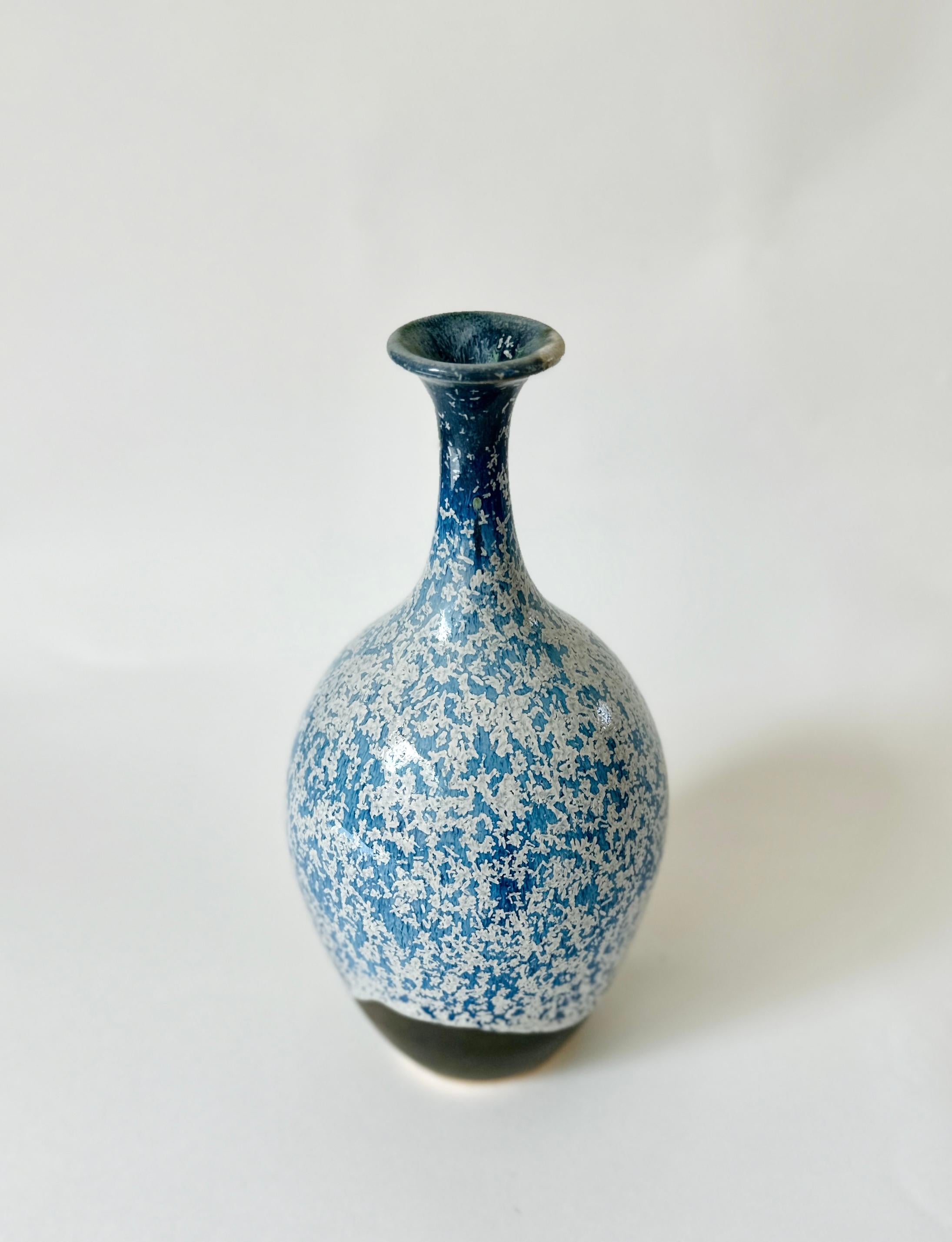 Wheel-thrown bottleneck vessel handmade by Dana Chieco and glazed with frosty blue and green/bronze glazes. This piece elegantly melds traditional craft with modern aesthetics, serving as a testament to the timeless beauty of heirloom
